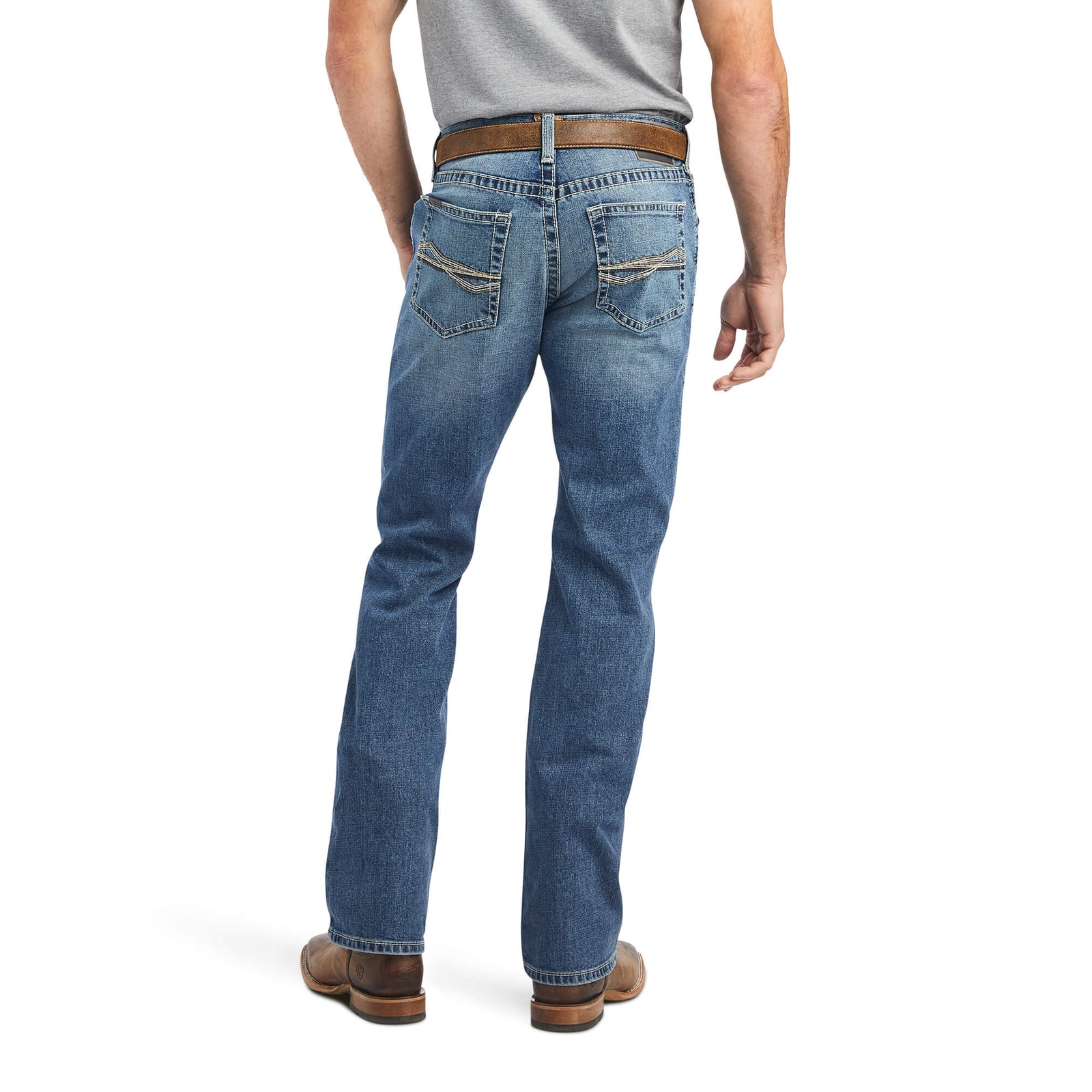 Ariat Men's M5 Bauer Straight Leg Jean. A man viewed from the back wearing blue straight leg jeans with a belt and tan cowboy boots.