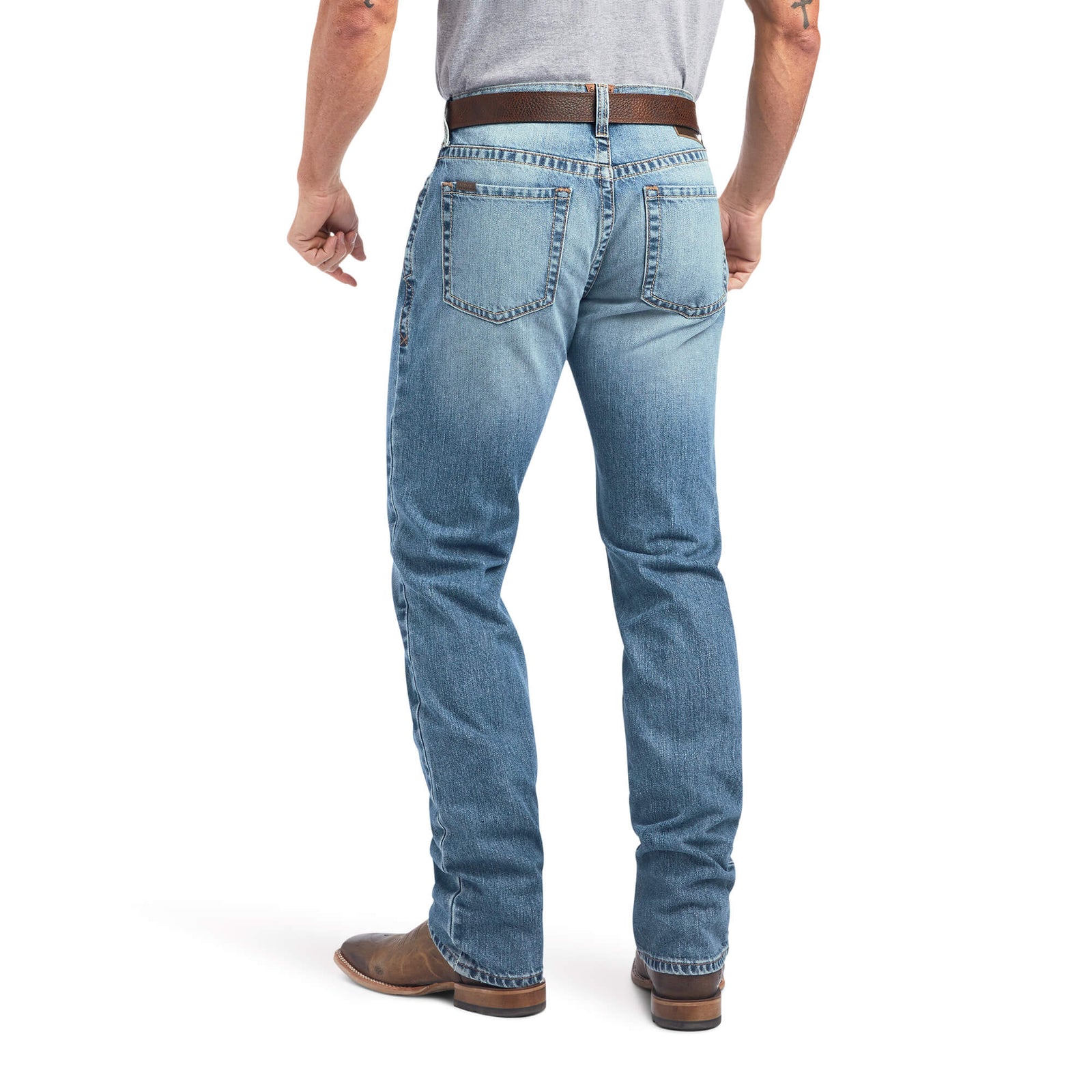 A man wearing Ariat Men's M4 Madera Relaxed Fit Jean, standing with one hand in pocket and looking to the side.