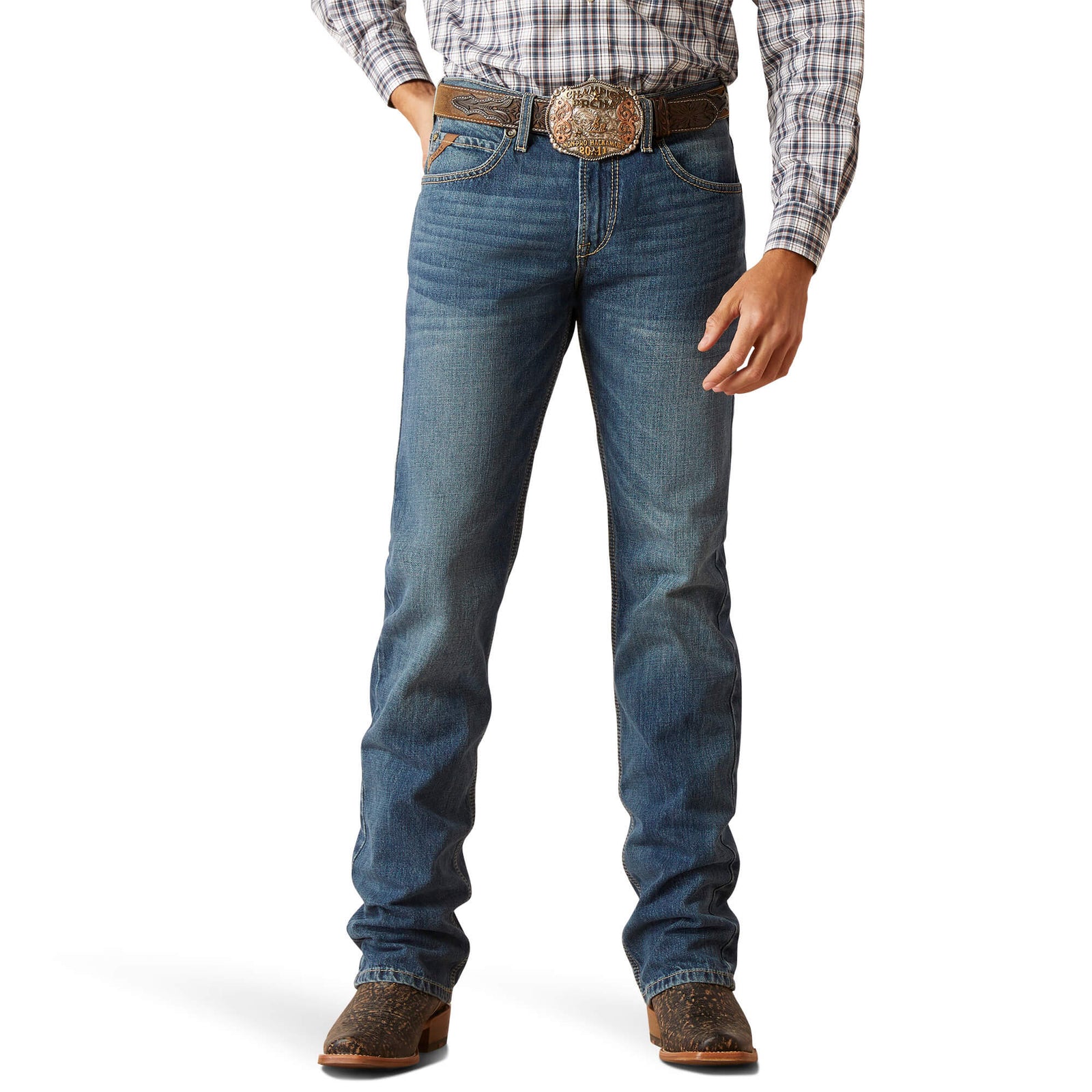 A man standing straight, wearing Ariat Men's M7 Ezra Slim Fit Straight Leg Jean, a checkered shirt, and brown boots.