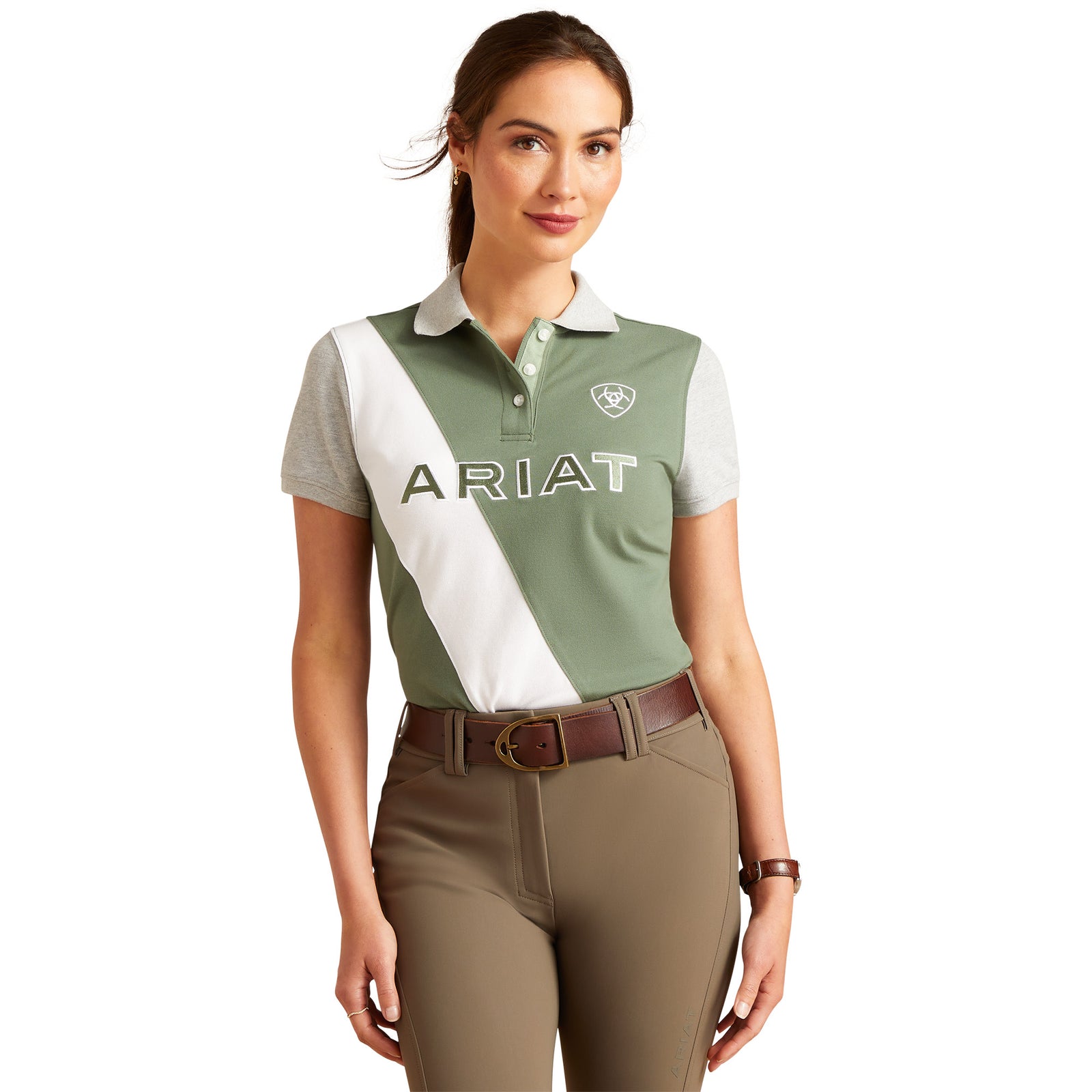 Ariat Women's Taryn S/S Polo. A woman wearing an Ariat brand polo shirt in green, white, and gray color blocking. The shirt features logo embroidery and contrast color blocking.