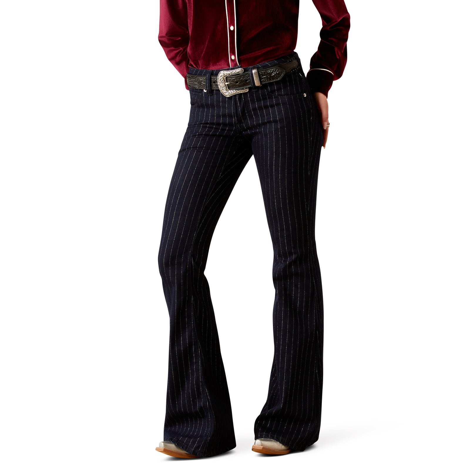A woman wearing Ariat Women's Perfect Rise Jasmine Flare Jean with silver metallic pinstripes, the jeans have a slim fit through hip and thigh with a flared silhouette below the knee.