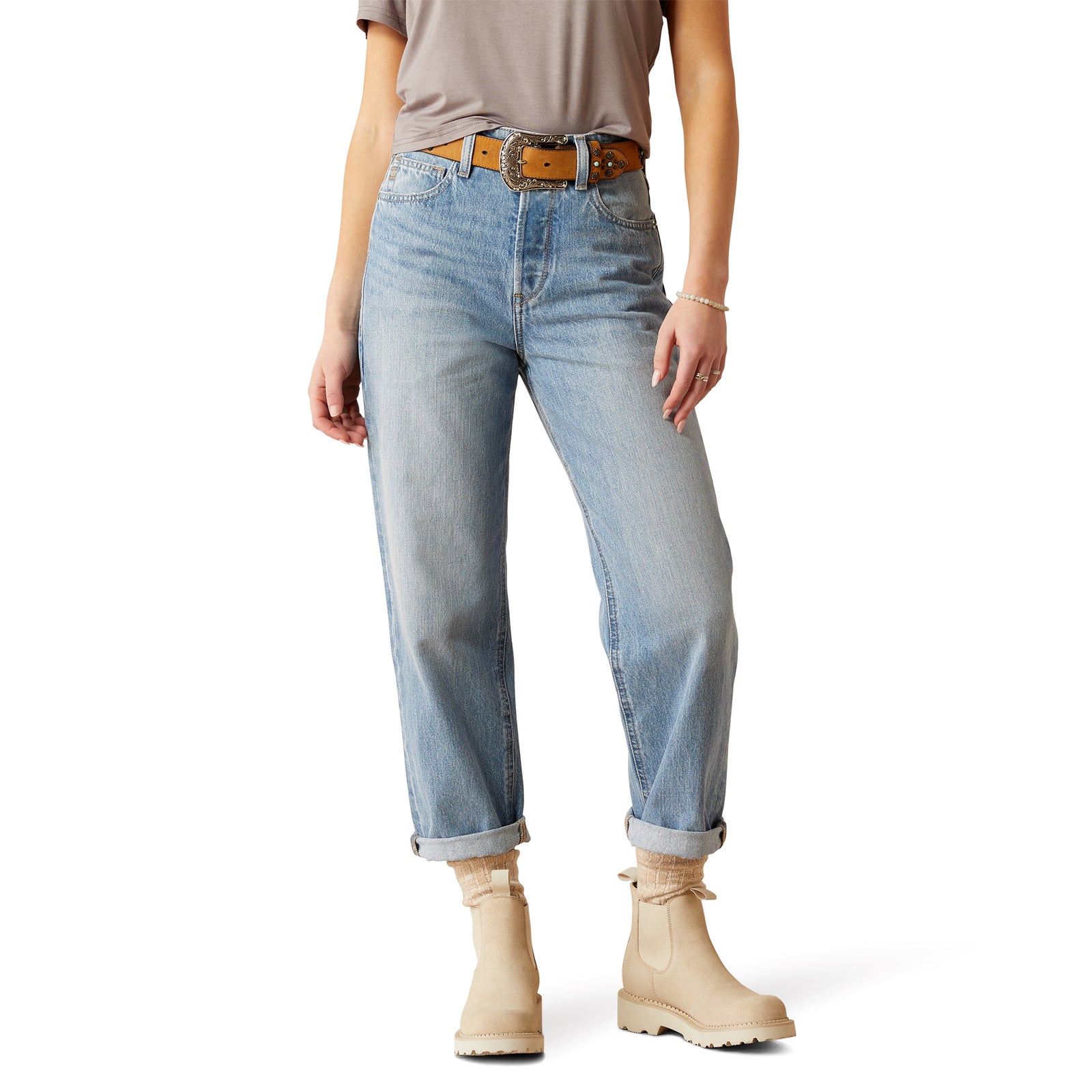 Ariat Women's Ultra High Rise Tomboy Straight Leg Jean. A woman wearing ultra high-rise tomboy straight leg jeans with a light wash and rolled-up hem, paired with a grey top and boots.