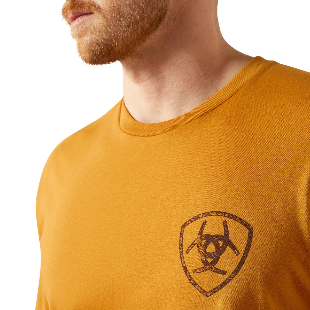 Man wearing a mustard yellow t-shirt with a logo on a white background