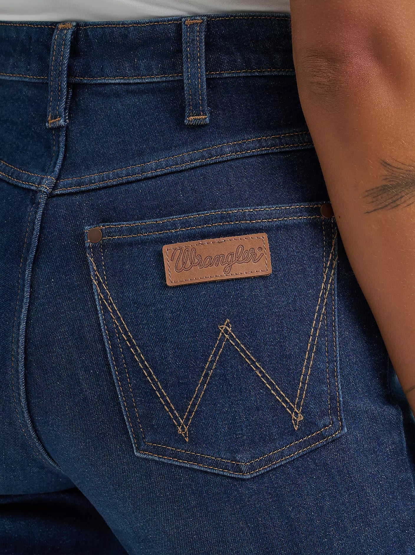 Close-up of blue jeans with a Wrangler logo on the pocket.
