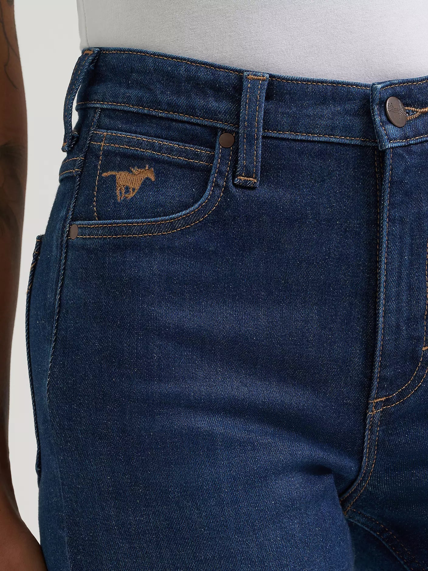 Close-up of blue jeans with a brand logo on the pocket against a white background