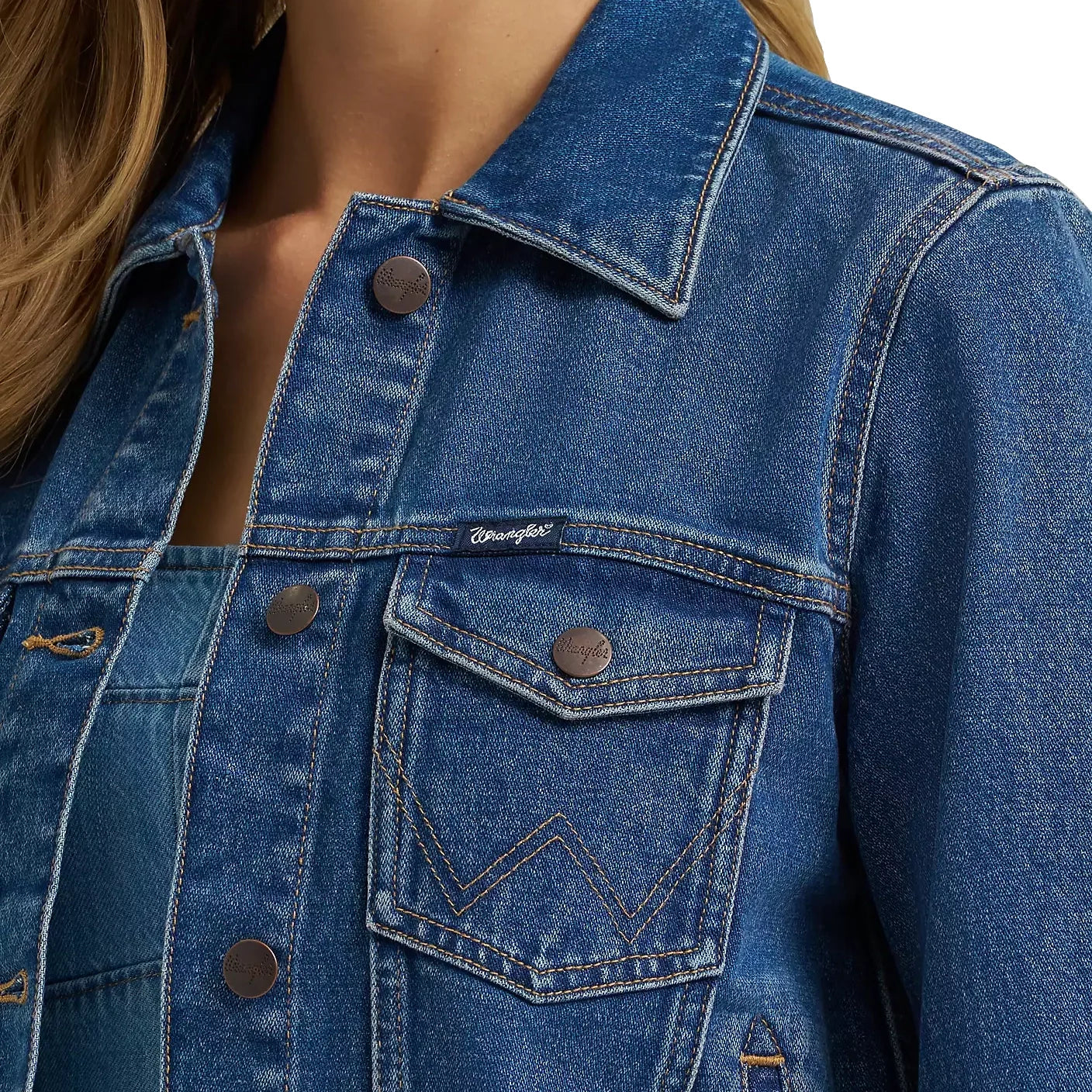 Close-up of a blue denim jacket with a brand logo on the chest pocket.