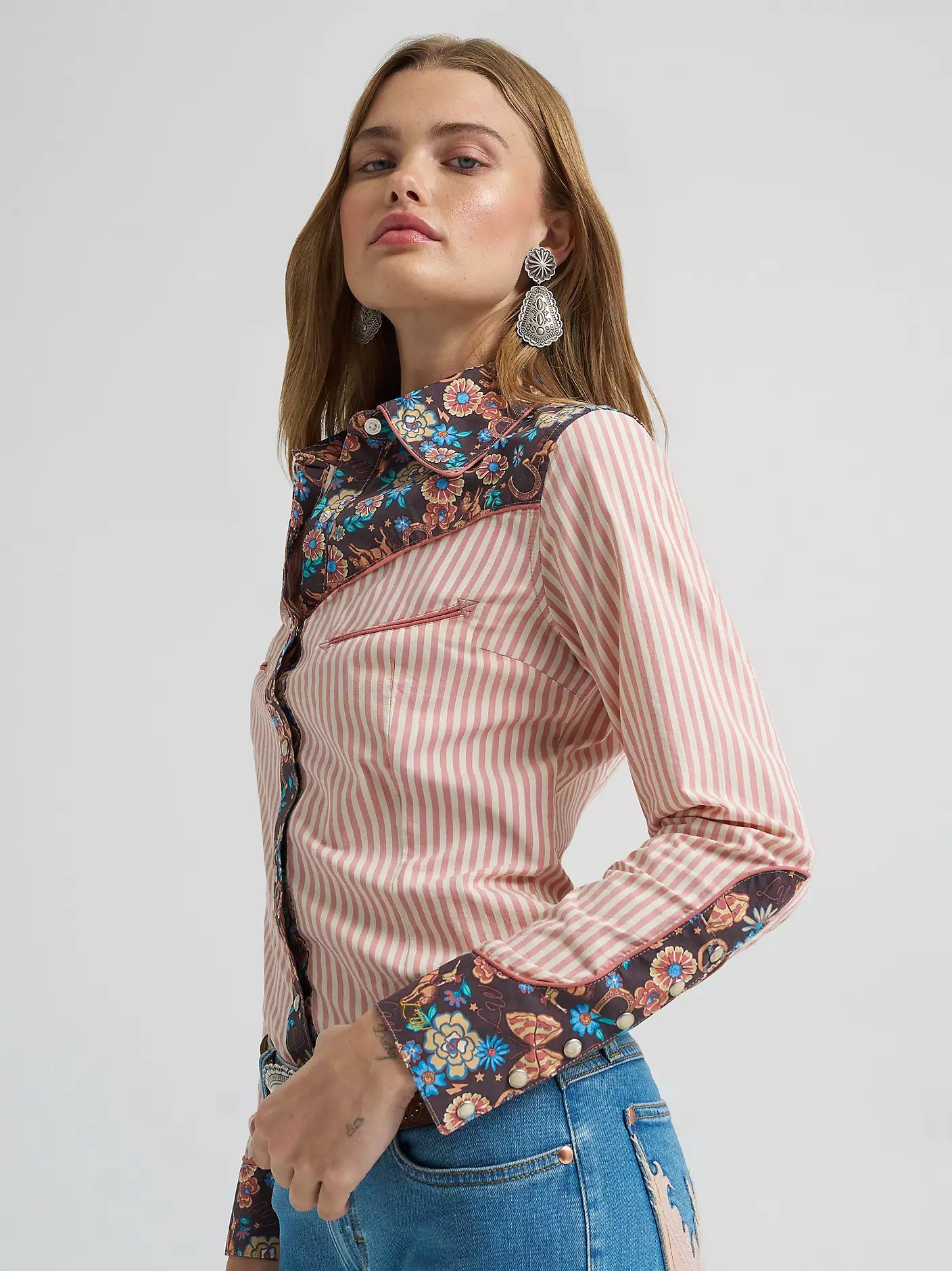 Woman wearing a pink striped shirt with floral embroidery on a white background
