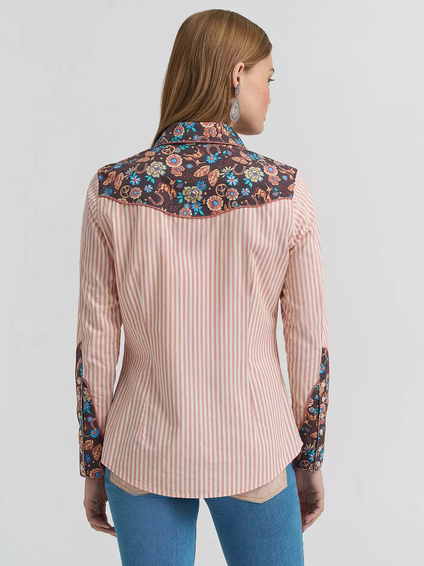 Woman wearing a pink striped shirt with floral accents on a white background