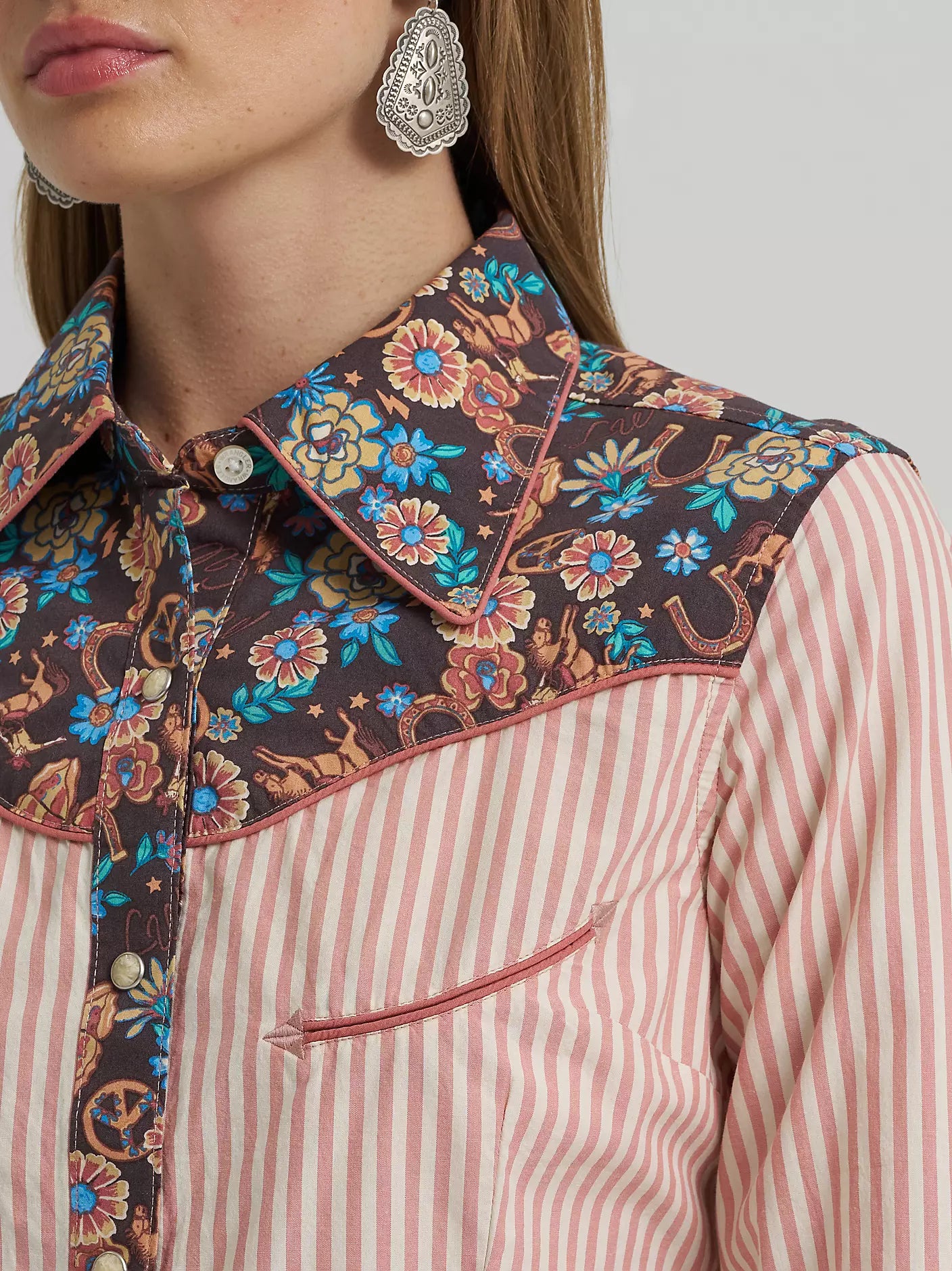 Close-up of a person wearing a floral-patterned vest over a striped shirt.