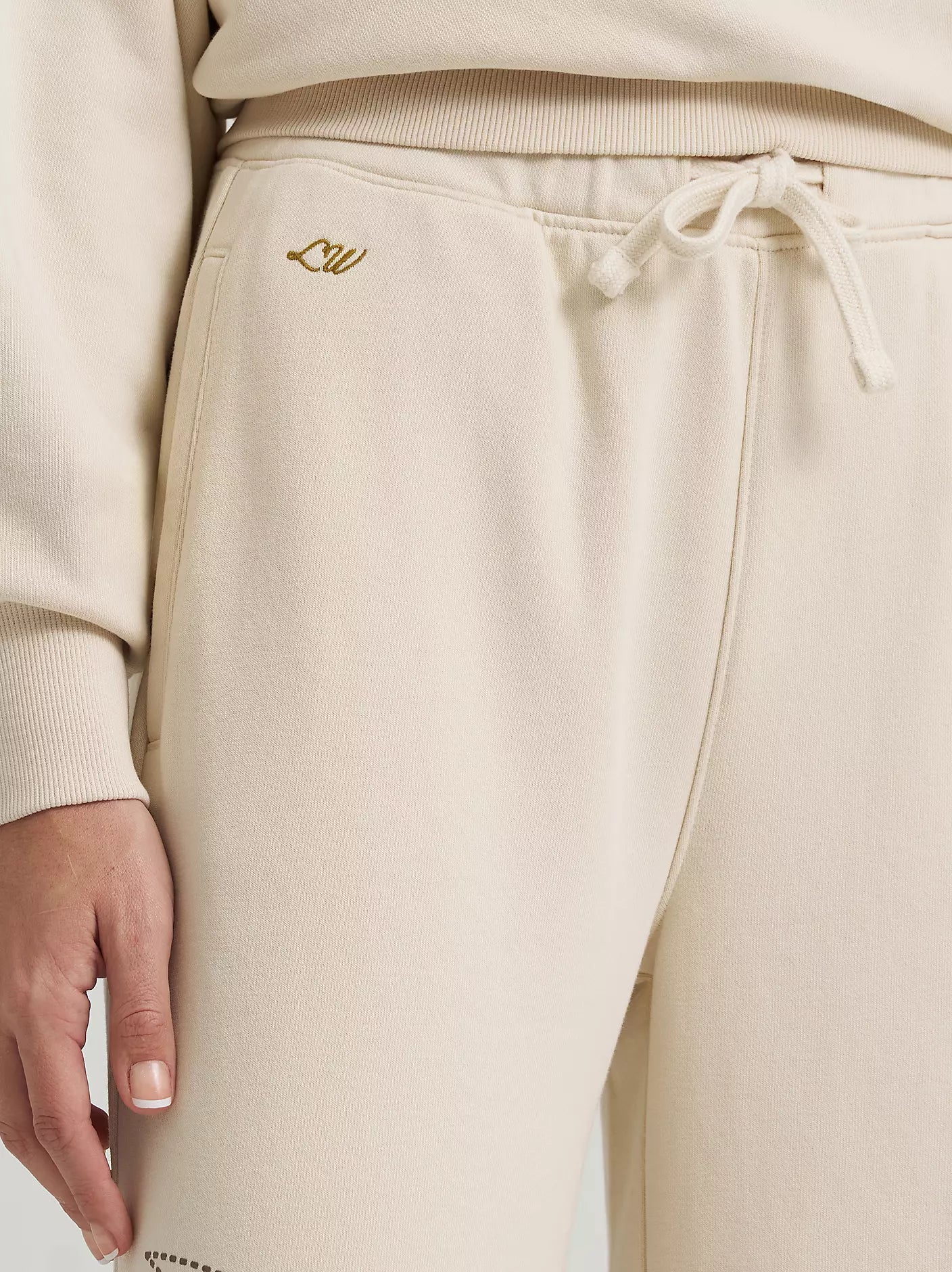 Beige sweatpants with a drawstring and logo on a plain background