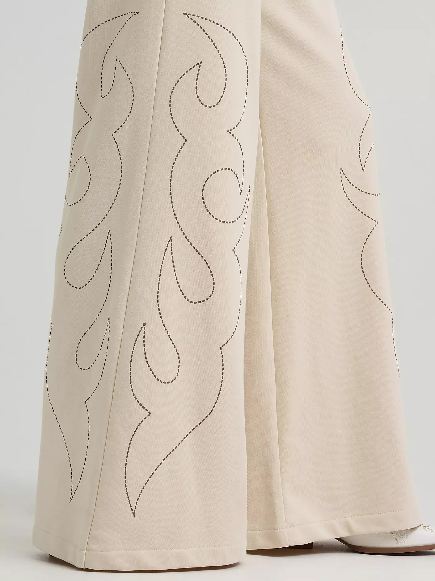 Beige pants with decorative stitching on a light gray background