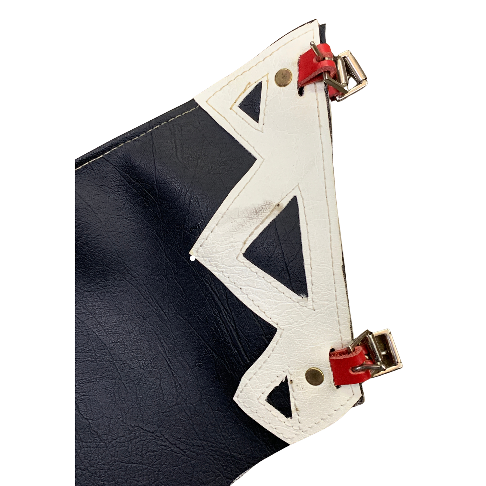 Close-up of a handbag corner showing a dark navy blue textured leather body, a white geometric cutout overlay, and small red accent tabs with gold-tone metal hardware on a white background.