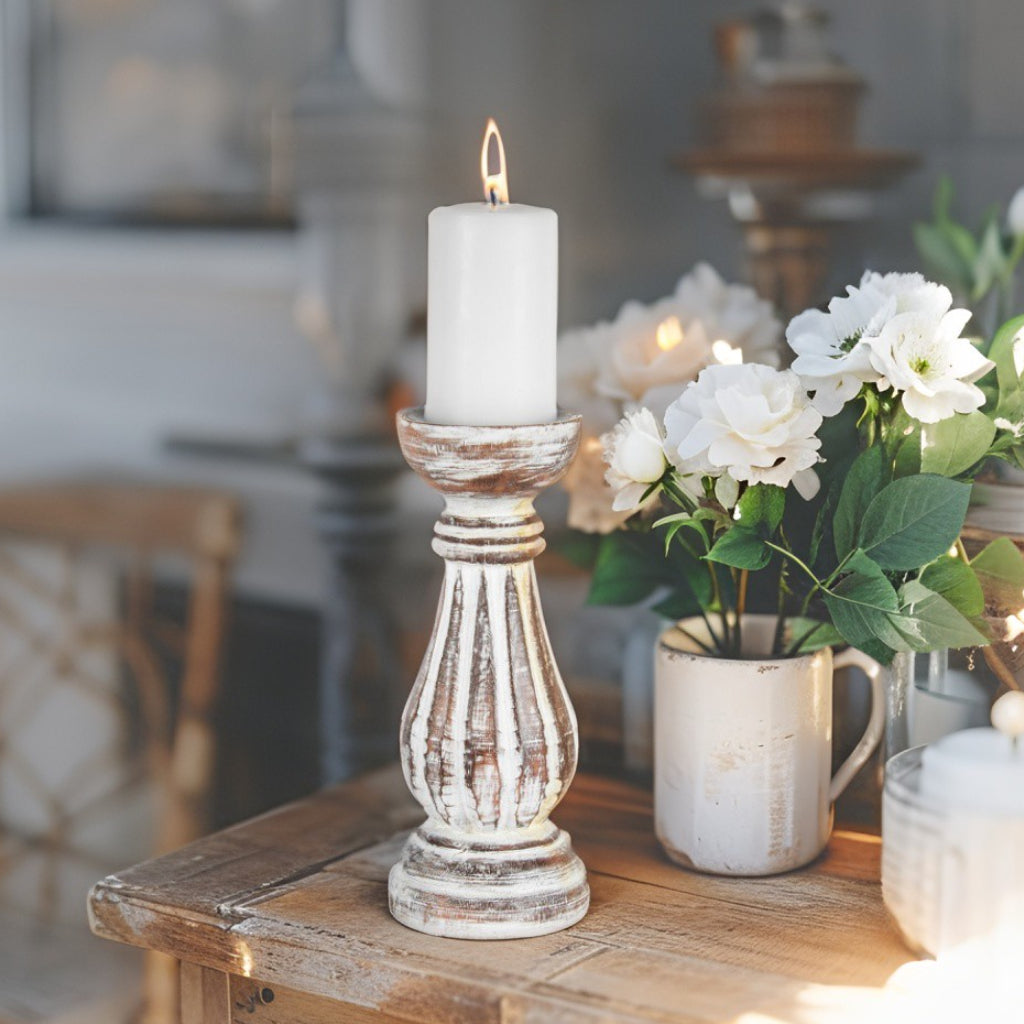 Hand Carved Candleholder. White candle in a rustic wooden holder on a wooden table with flowers in the background