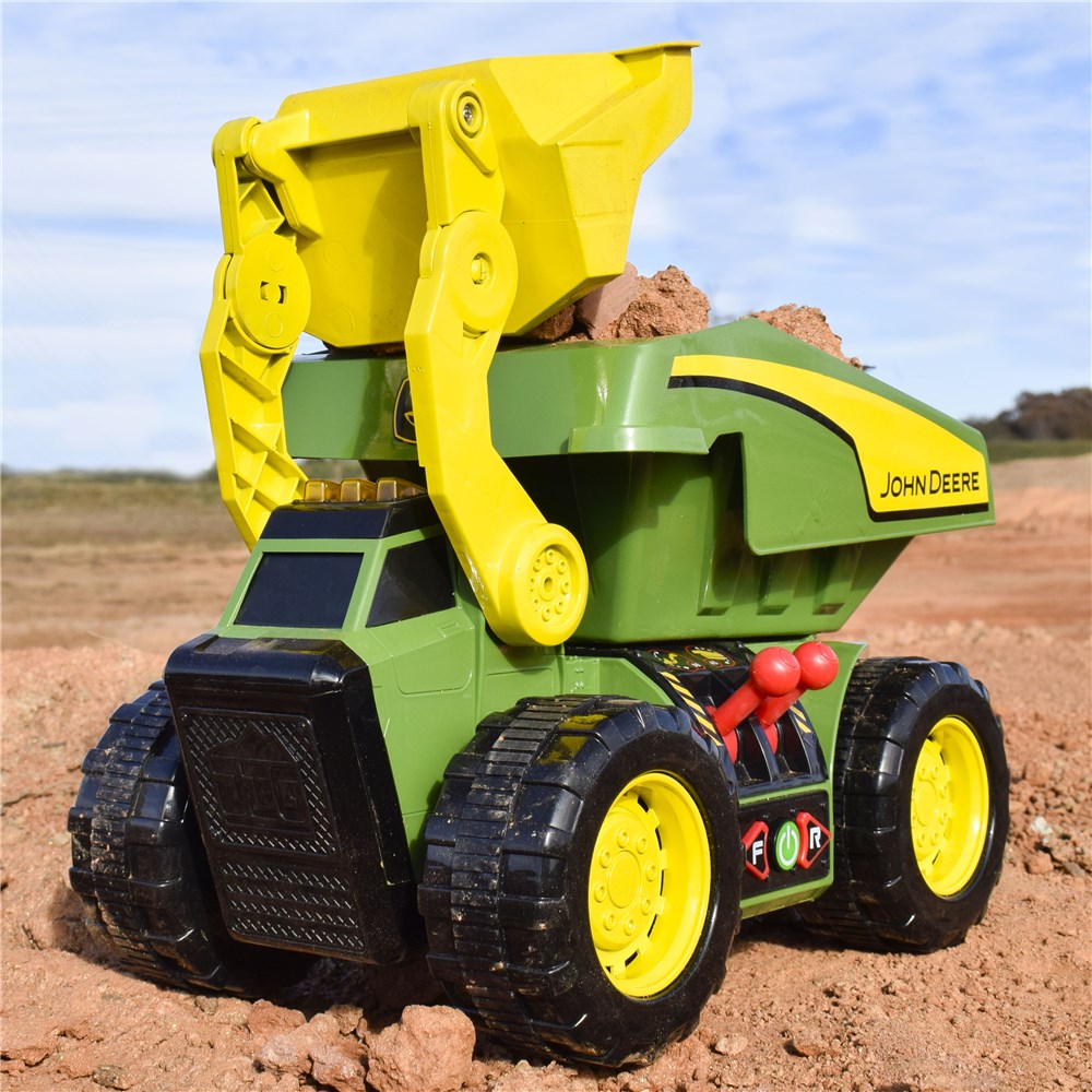 John Deere 46cm Motorised 'Lights & Sounds' 2-n-1 Dig & Dump Rig. Toy dump truck with yellow and green colors on a dirt background