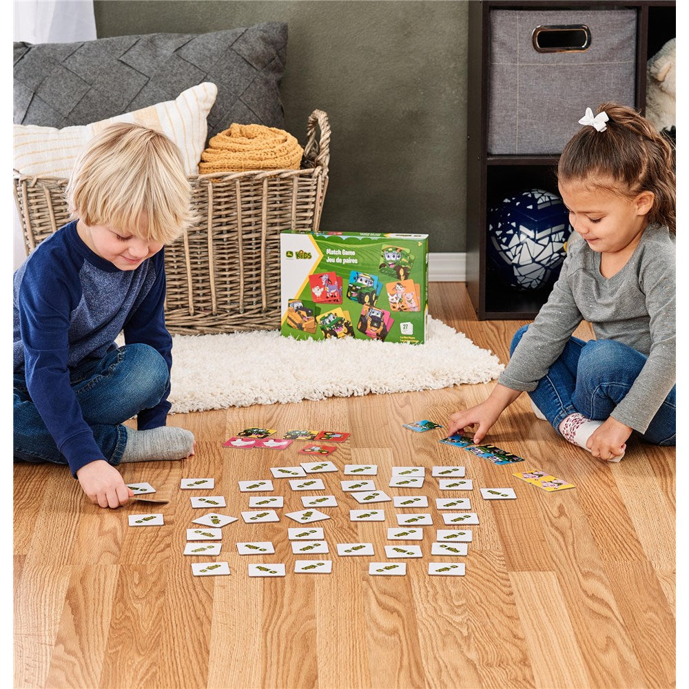Two children playing with a board game on a wooden floor.