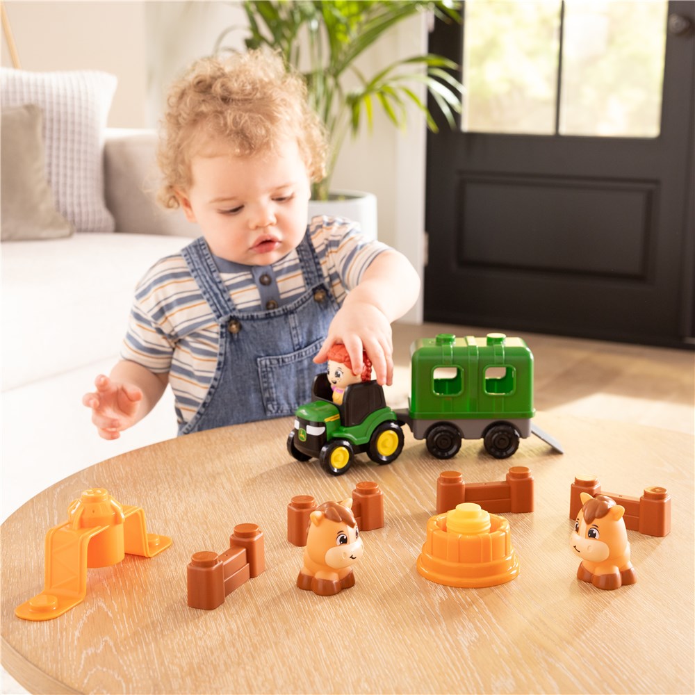 Child playing with toy farm set on a wooden table