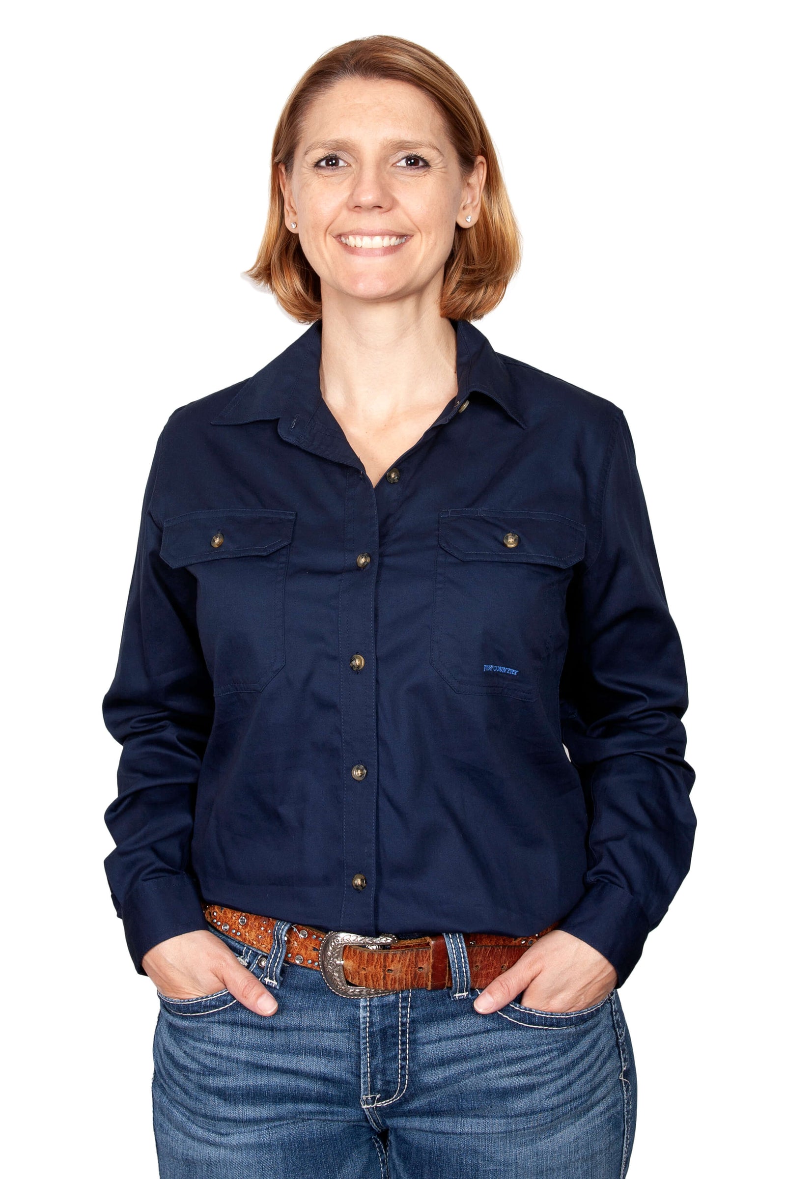 Just Country Women's Brooke Workshirt. A woman wearing a navy blue long-sleeved Just Country workshirt with long tails, double pockets, and a full button front.