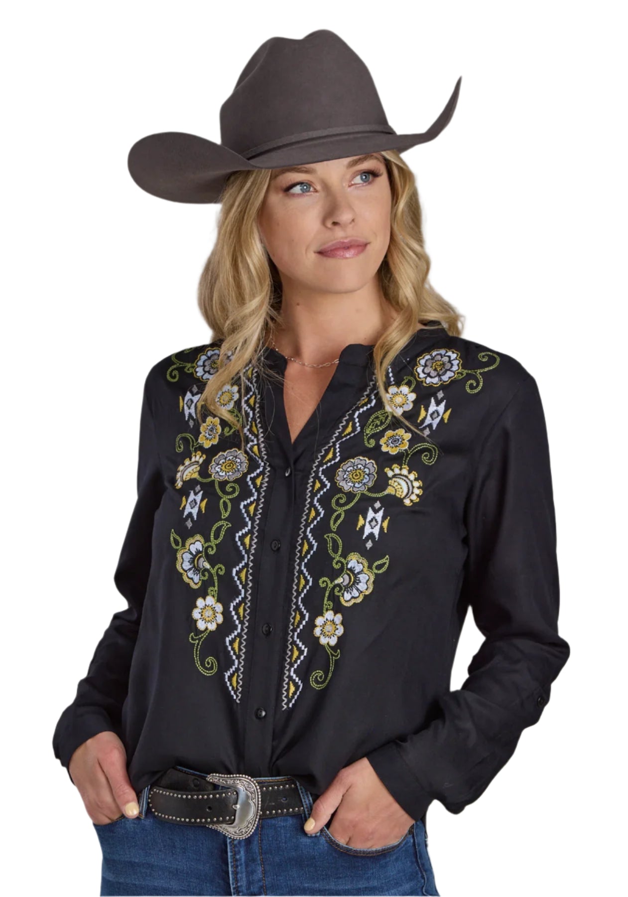 Roper Women's Studio West L/S Blouse. A woman wearing a black long-sleeved blouse with colorful floral embroidery, a banded collar, and a button front closure. She is also wearing blue jeans and has a cowboy hat on.