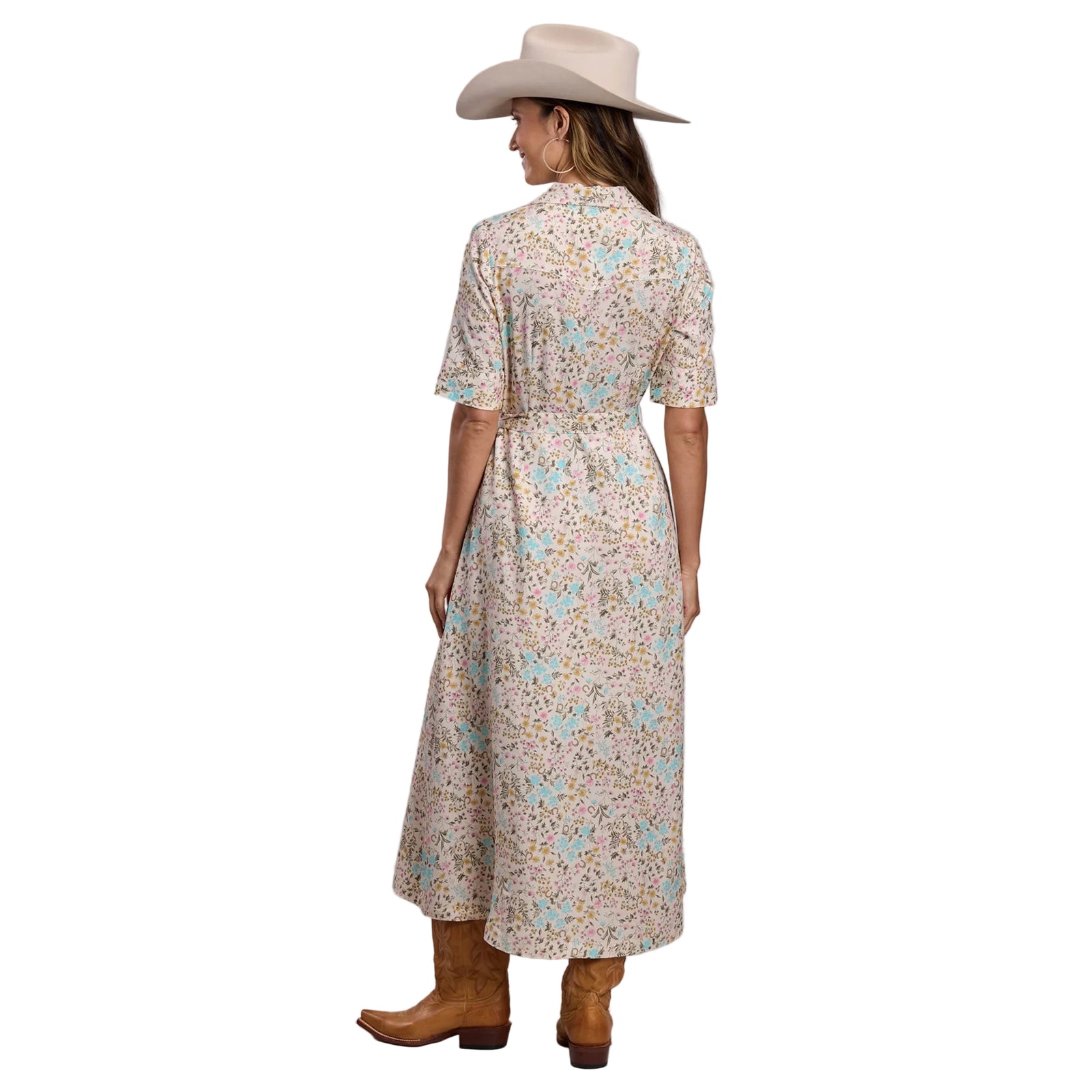 Woman wearing a floral dress, cowboy hat, and boots on a plain background