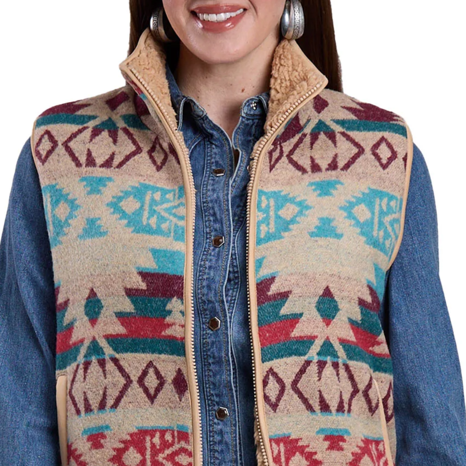Person wearing a patterned vest over a denim shirt on a white background
