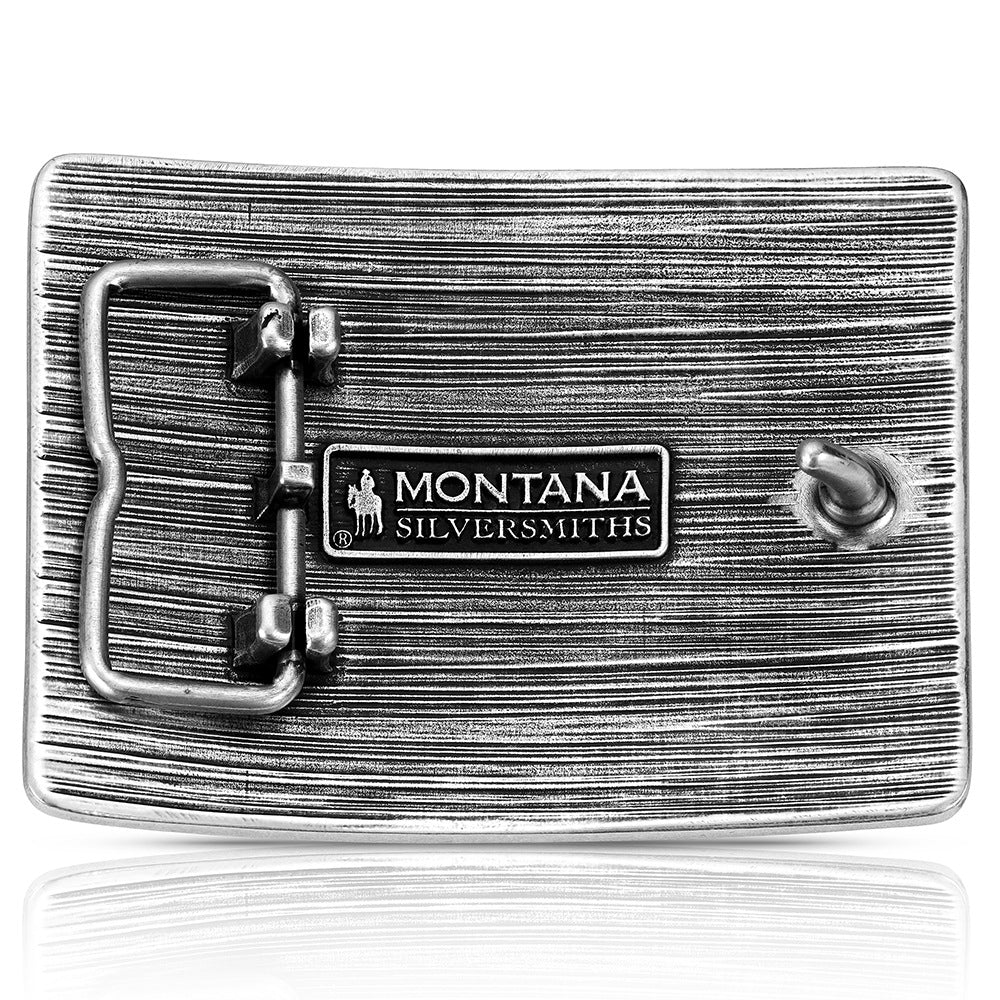 A silver-toned textured belt buckle featuring a central rectangular plate engraved with 'MONTANA SILVERSMITHS' and the company's cowboy logo, shown on a reflective white background.