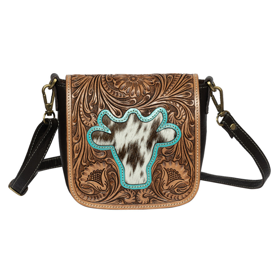 The Design Edge Women's Bullhead Sling Bag. A brown leather sling bag with a tooled leather bullhead design on the flap, a black shoulder strap, and intricate hand tooling.