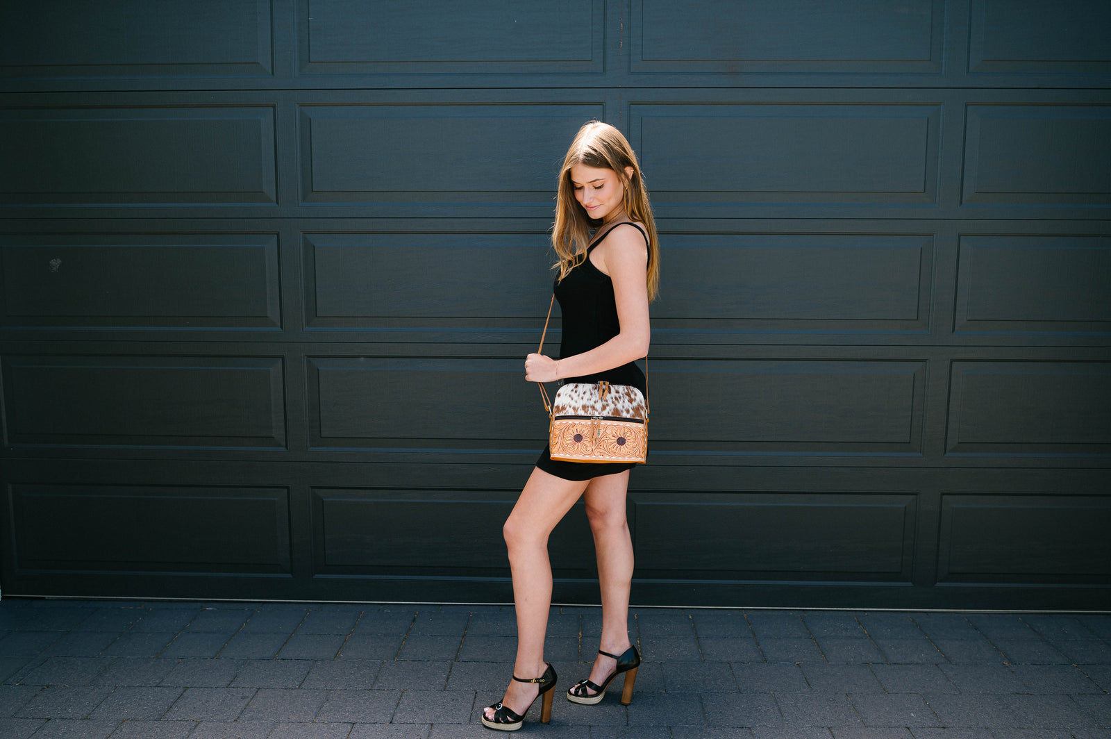 Woman holding a patterned handbag against a dark wall