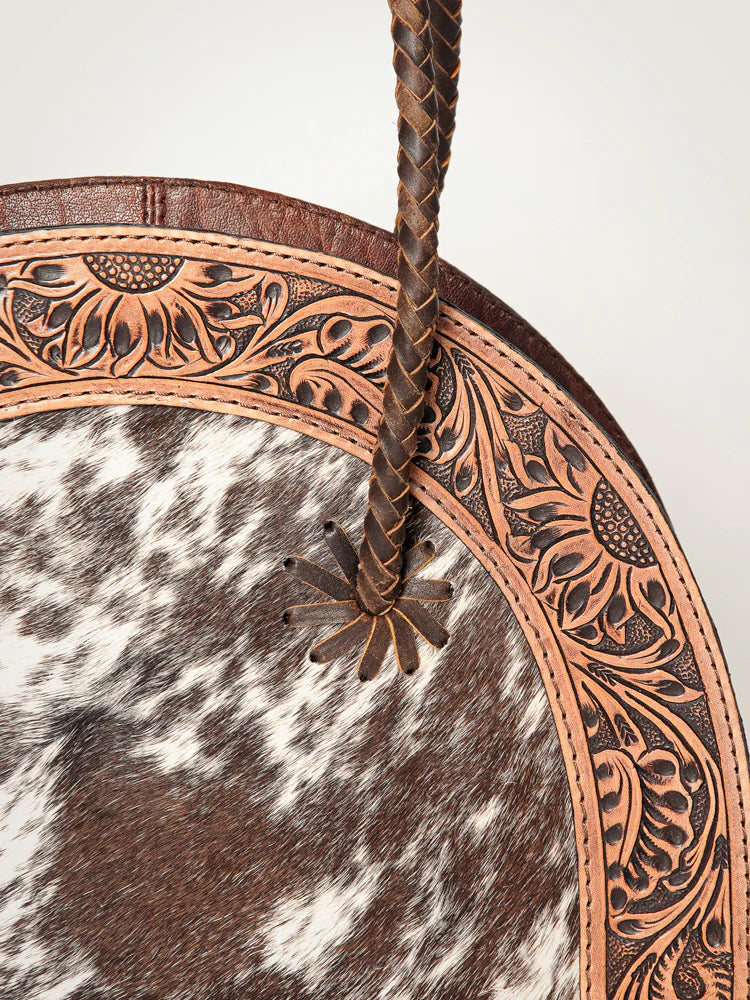 American Darling Tooled & Hide Western Tote. Decorative leather belt with intricate patterns on a cowhide background
