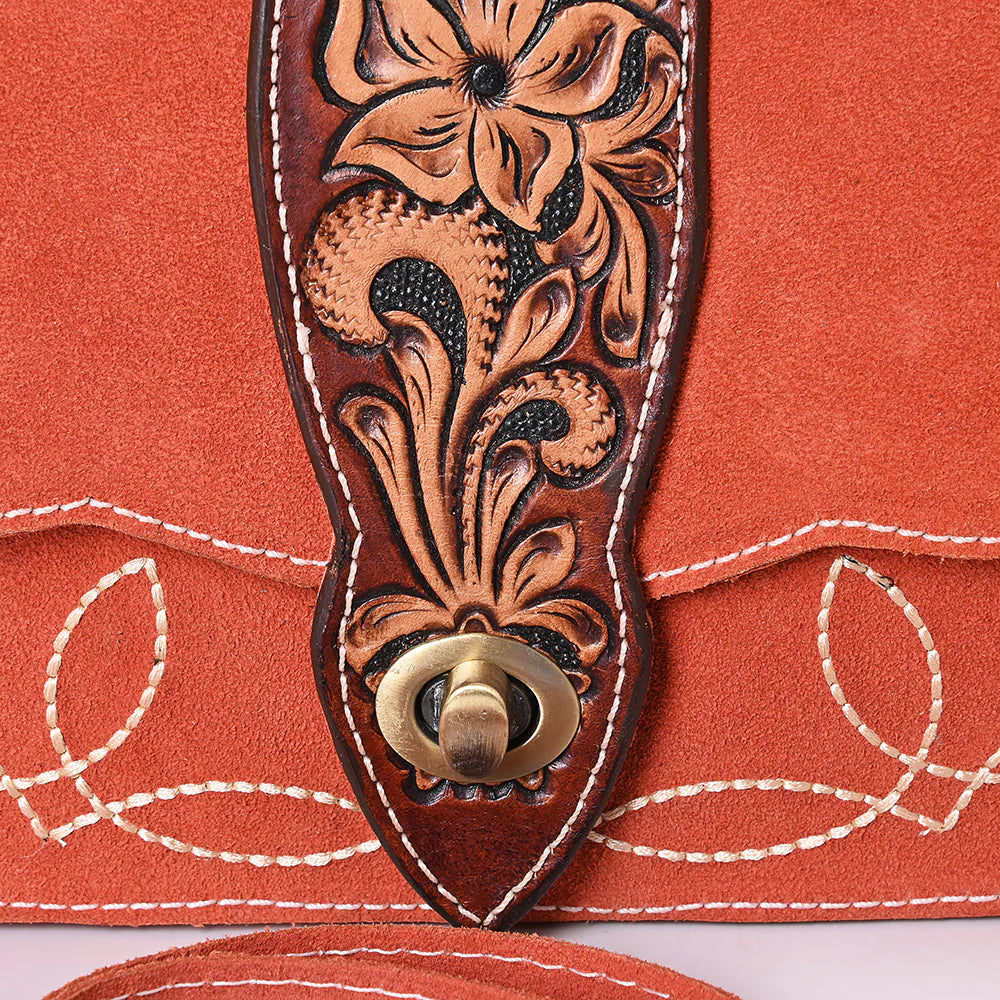 American Darling Burnt Orange Suede Western Shoulder Bag. Close-up of a brown leather strap with floral tooled design on an orange fabric background