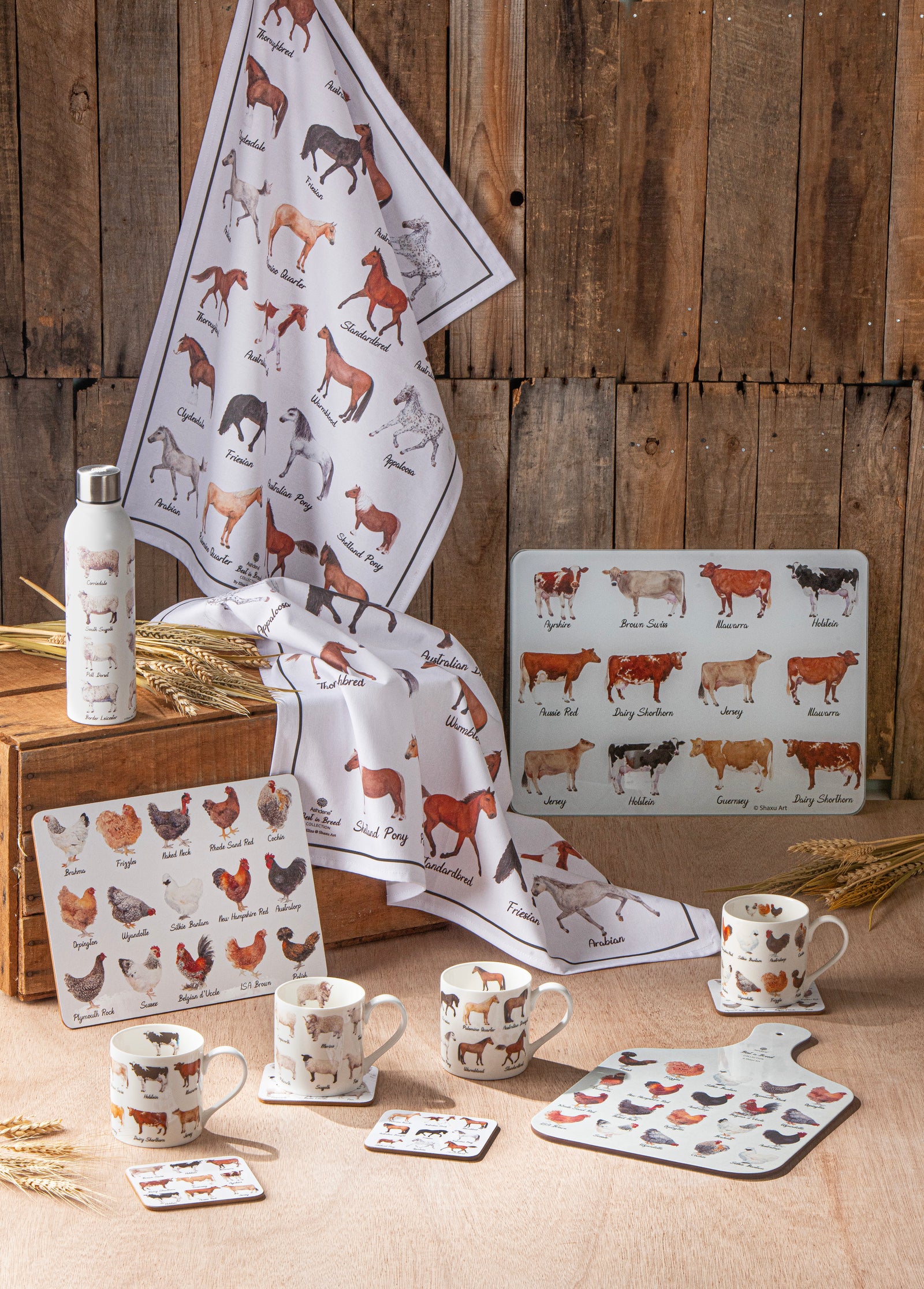 Set of farm-themed kitchen items including mugs, coasters, and a towel on a wooden surface.