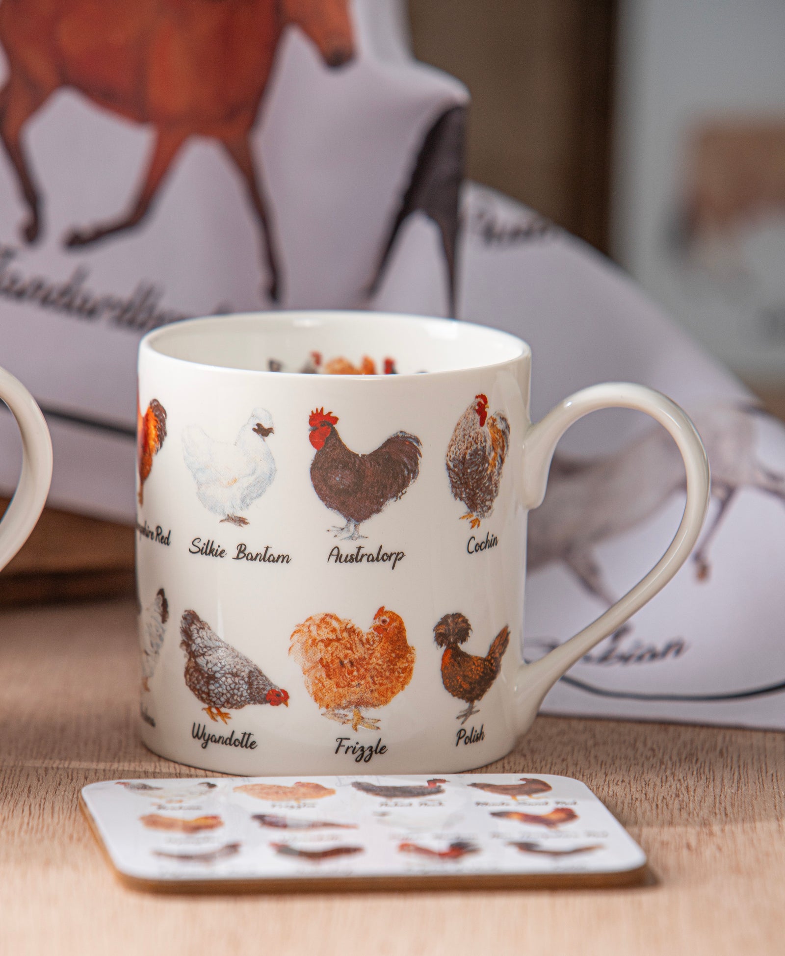 Mug with chicken breed illustrations on a table with a blurred background