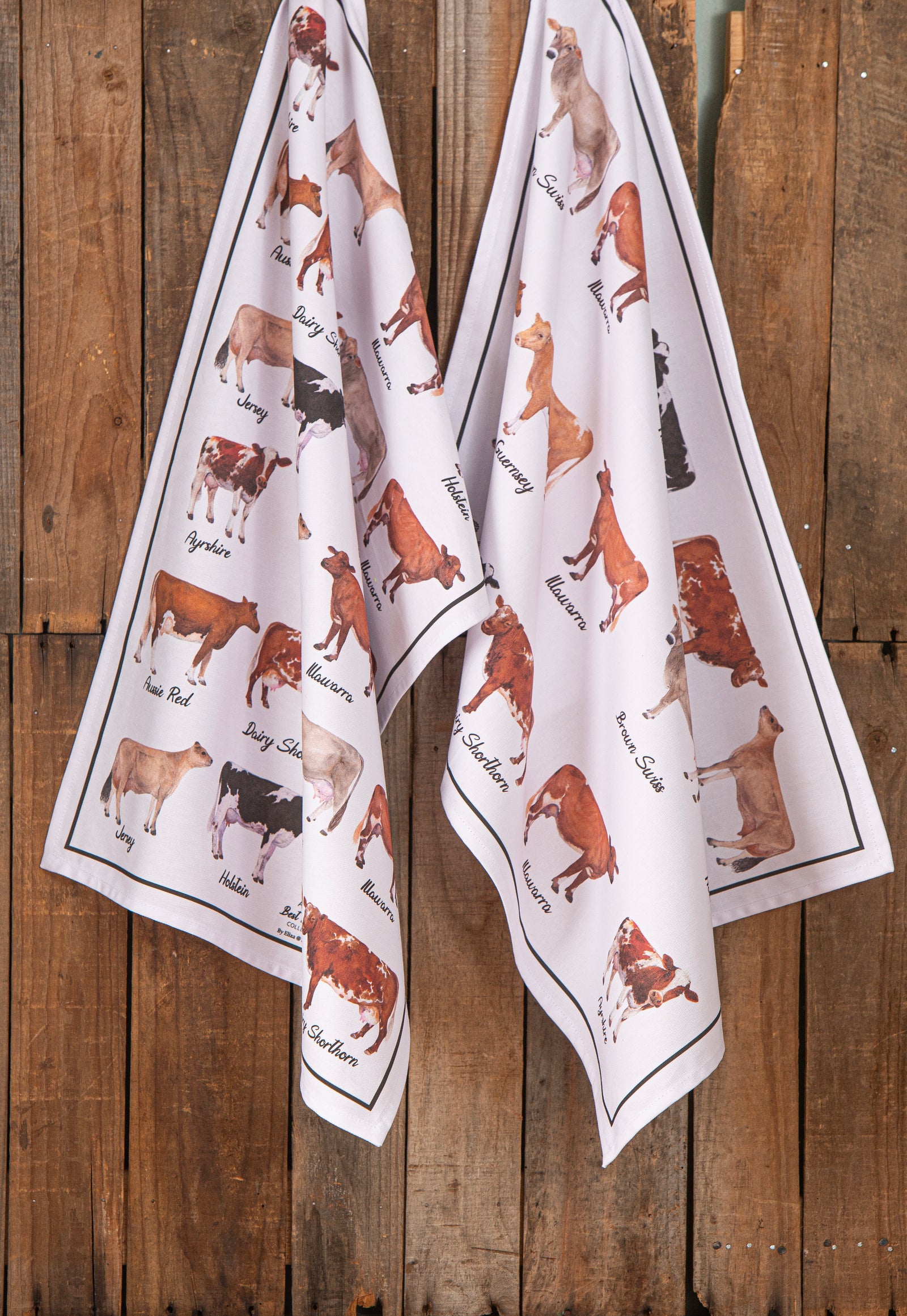 Two white towels with dog illustrations hanging on a wooden wall.