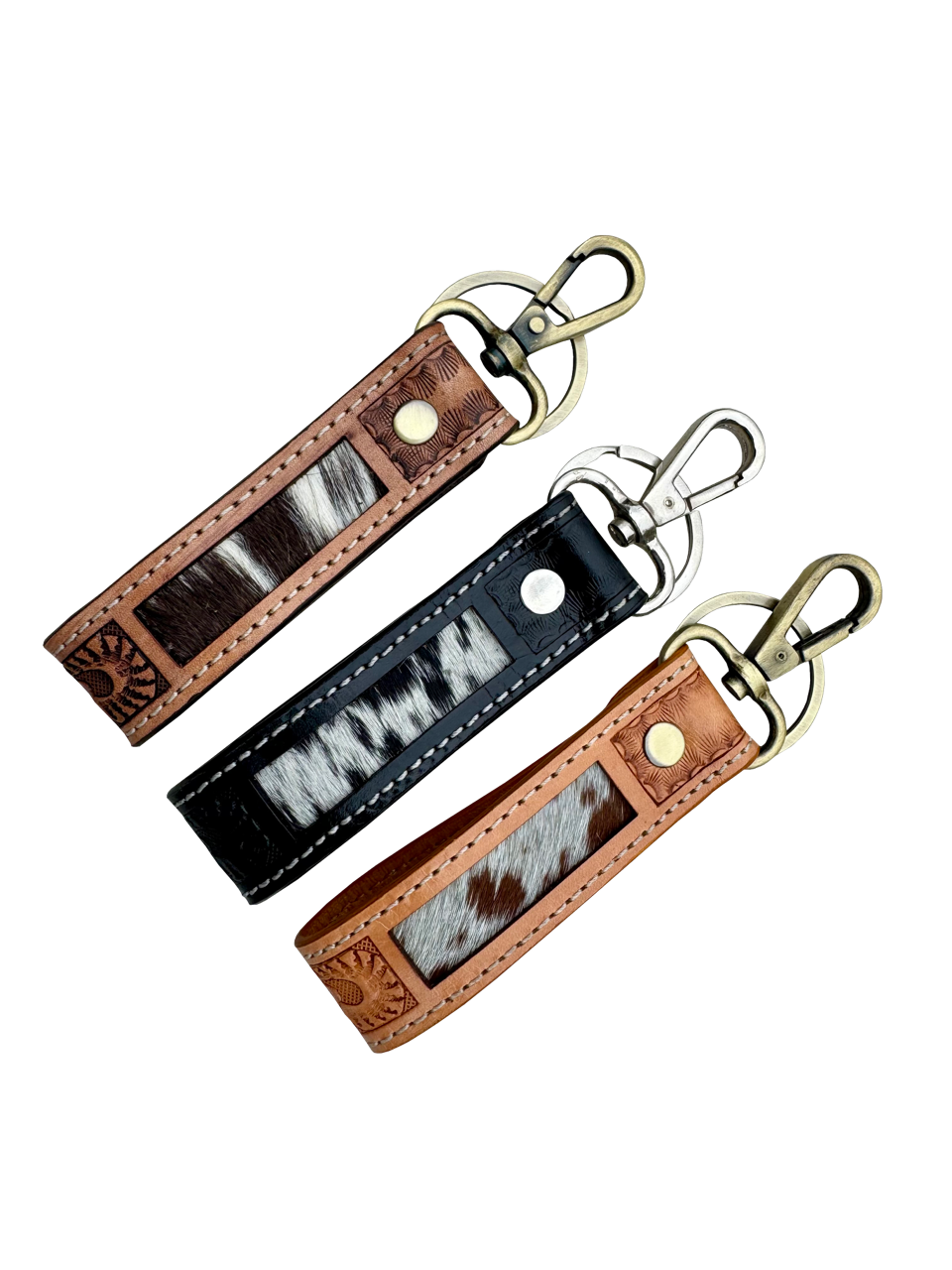 Tooling Leather and Cowhide Sleek Keyring. Three leather keychains with cowhide pattern on a white background
