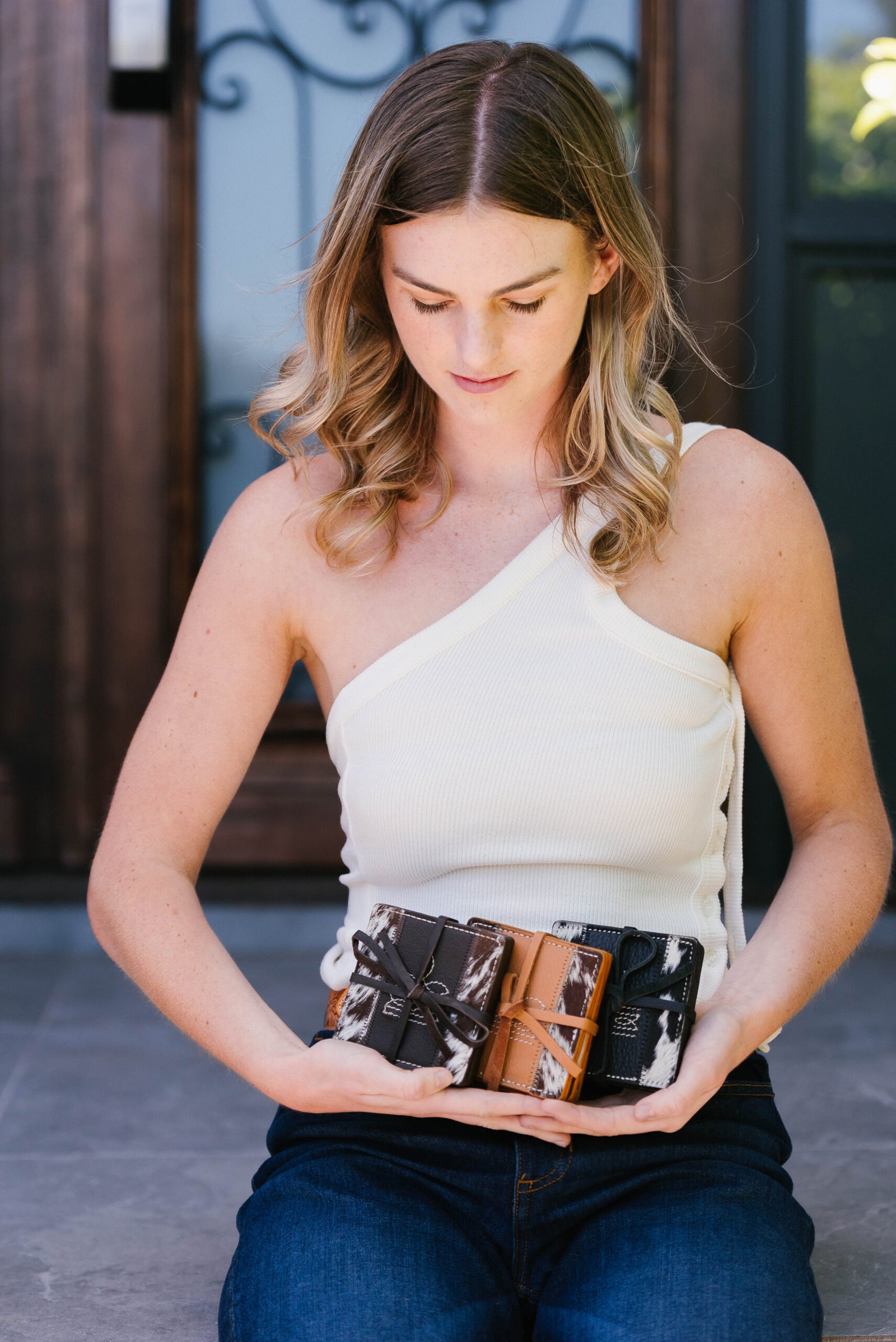 Woman holding a collection of leather wallets outdoors.