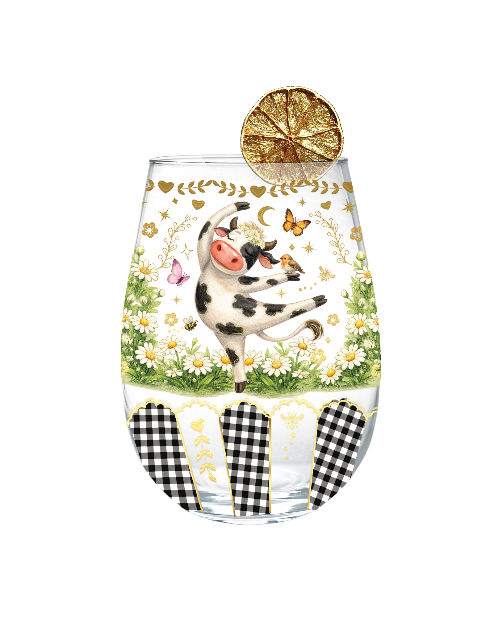 A clear stemless wine glass decorated with a whimsical illustration of a black-and-white cow dancing in a field of white daisies, surrounded by gold hearts, butterflies, and floral details. A dried orange slice garnish rests on the rim.