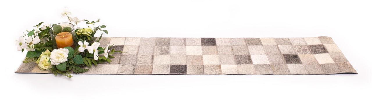 Cowhide Table Runner. Checkered table runner with floral arrangement and candles on a white background