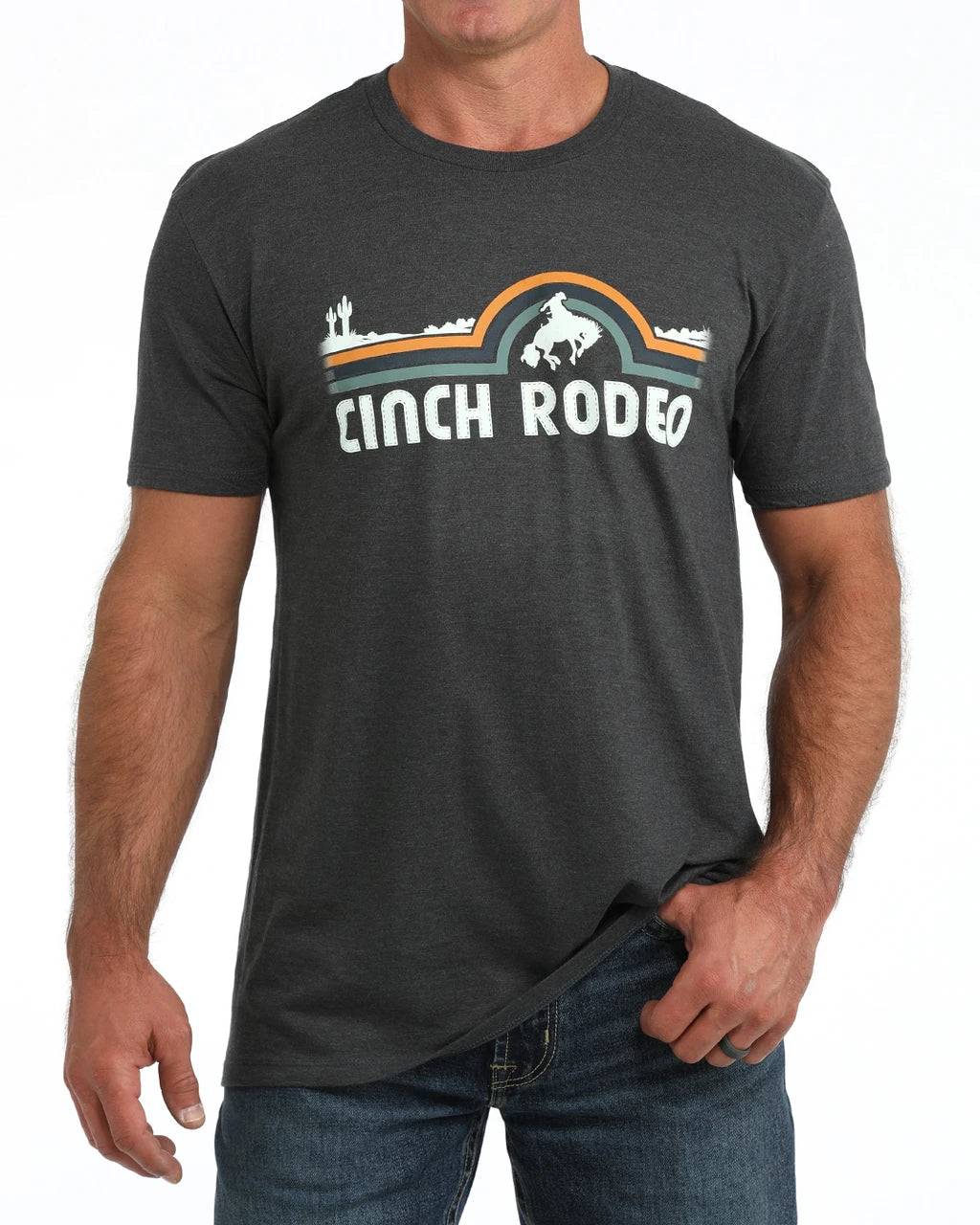 A man wearing a dark heather gray t-shirt with a retro western-style graphic that reads 'CINCH RODEO' with a cowboy on a horse and a sunburst design, paired with blue jeans against a plain white background.