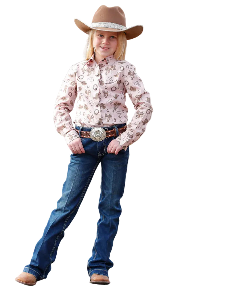 Child in cowboy attire with a patterned shirt and blue jeans standing in an outdoor setting.