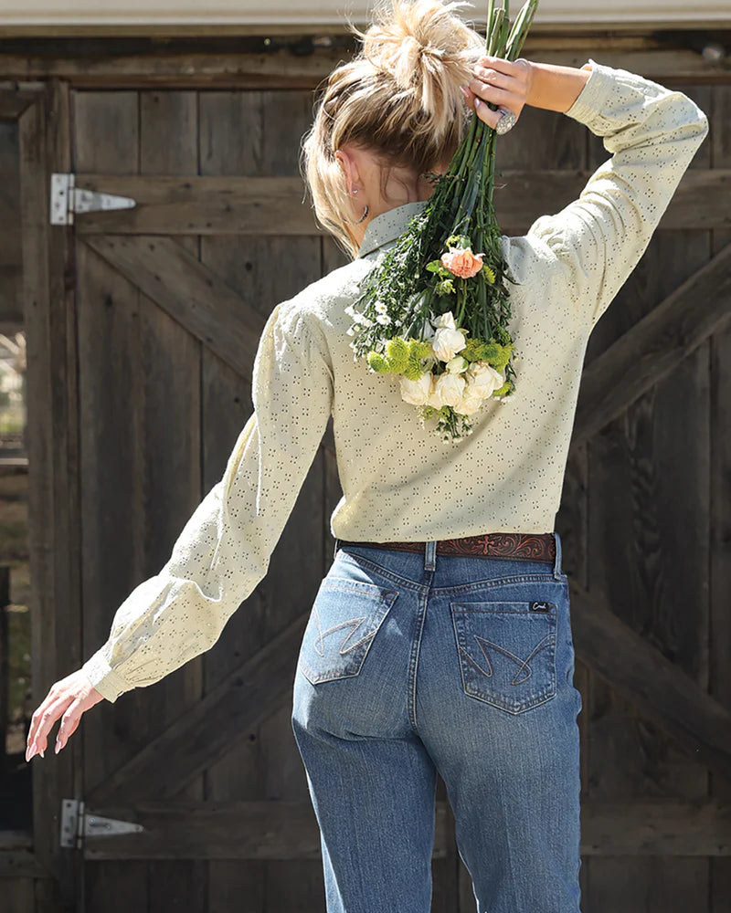 Woman holding flowers behind her back in front of a wooden door