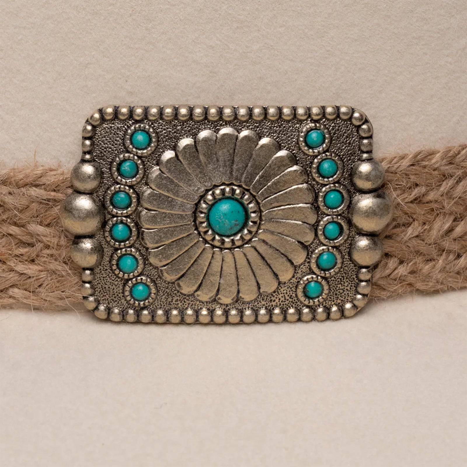 Charlie 1 Horse Fling Felt Cowboy Hat. A beige wool cowboy hat with a flat brim and a heart-shaped crown, featuring a metallic concho with turquoise ornamentation and a jute hatband.