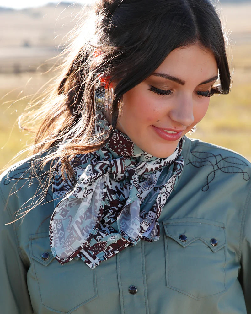 Woman wearing a patterned scarf and green jacket in a natural setting