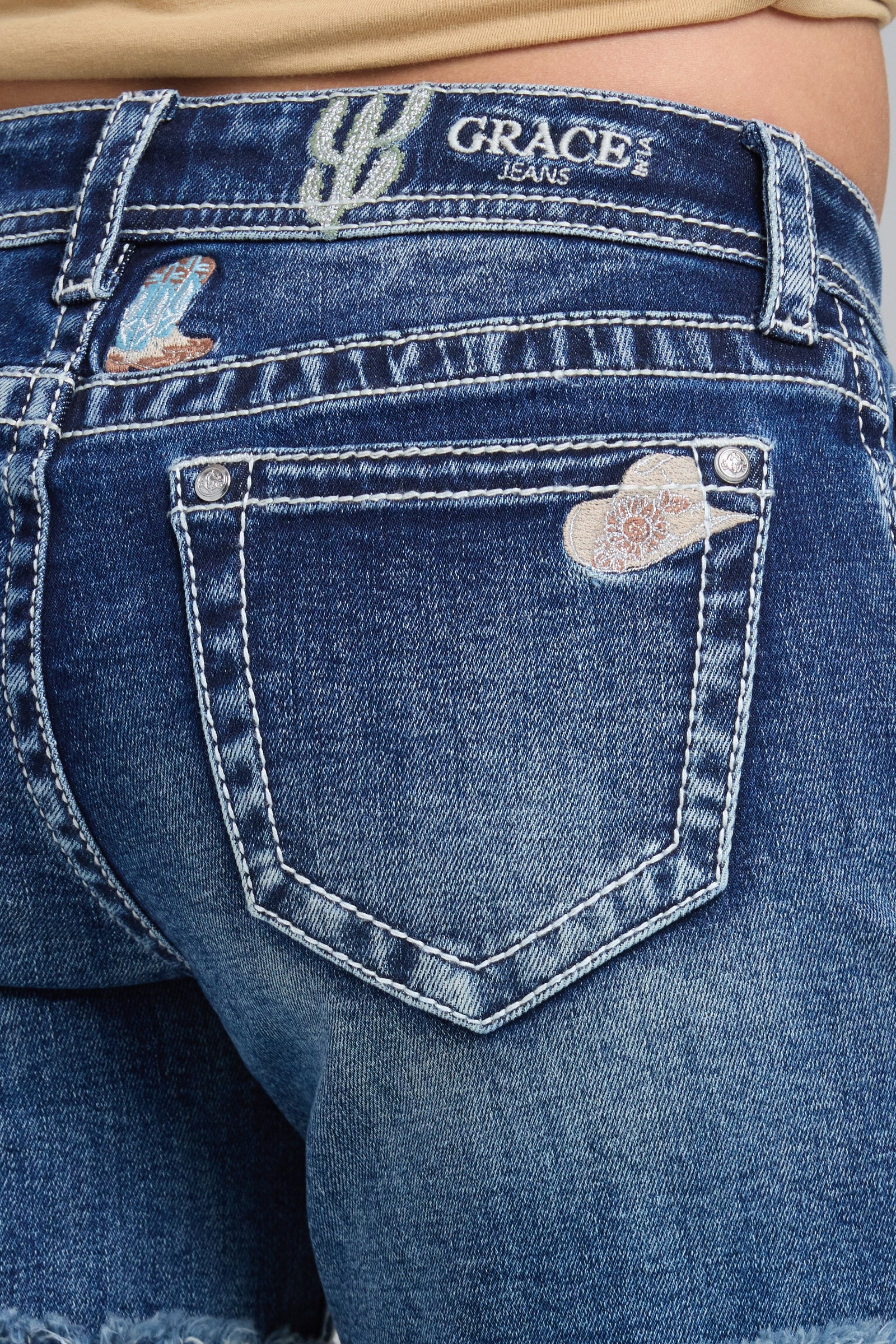 Close-up of blue jeans with 'Grace' branding on the back pocket.