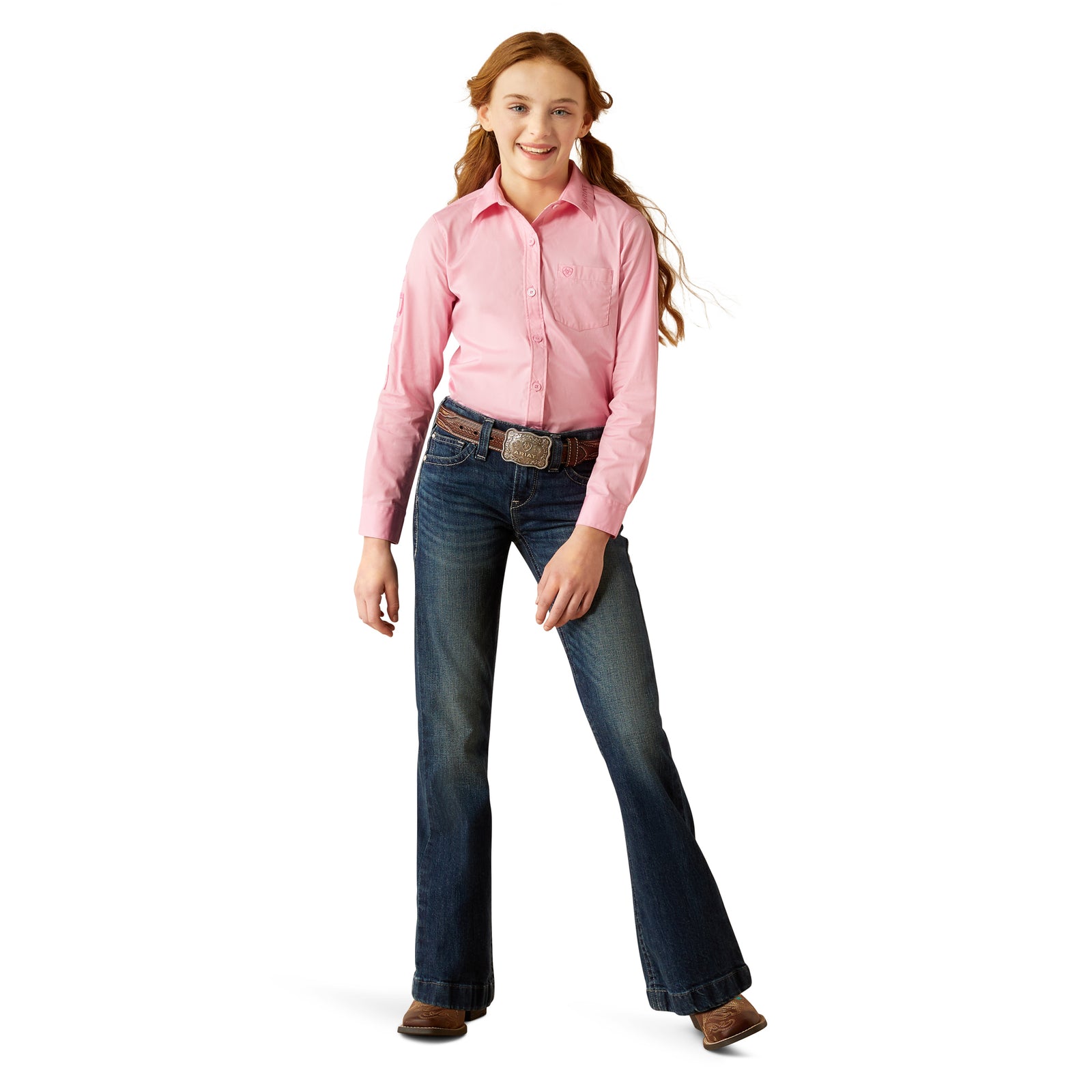 Ariat Girl's Team Kirby L/S Western Shirt. Person wearing a pink shirt and blue jeans on a white background