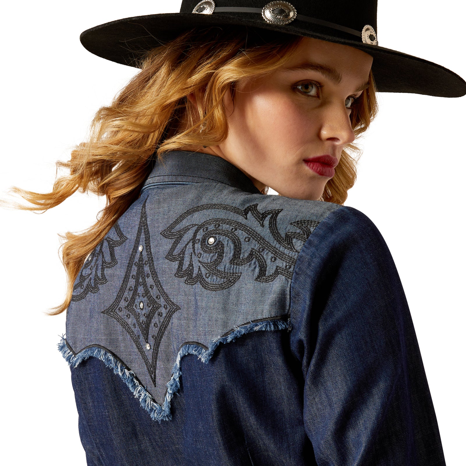 Ariat Women's Second Fiddle L/S Western Shirt. Woman wearing a denim jacket with embroidered back design and a cowboy hat.