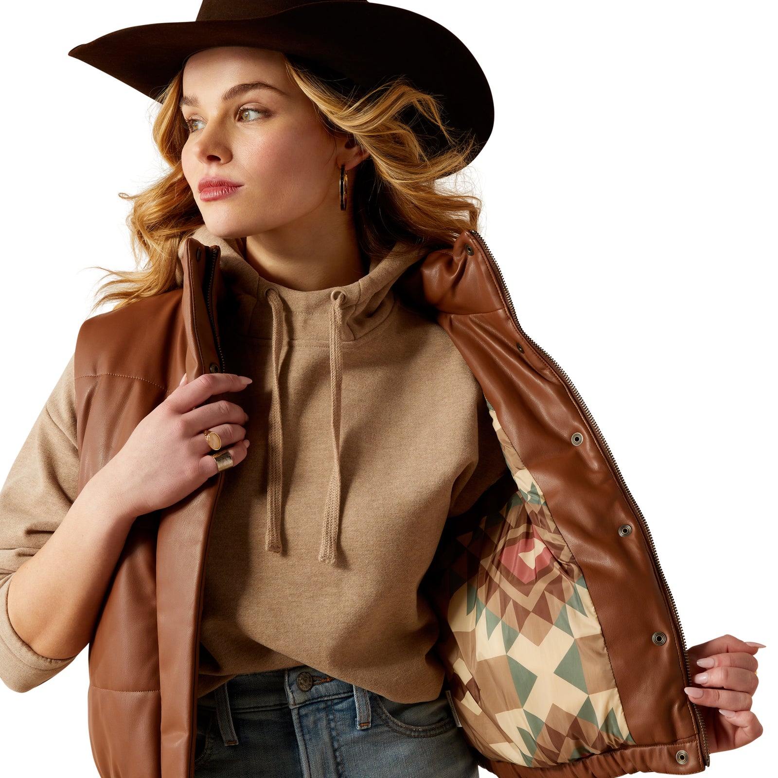 Ariat Women's Swirls Faux Leather Vest. Woman in brown hat and leather jacket holding a patterned bag