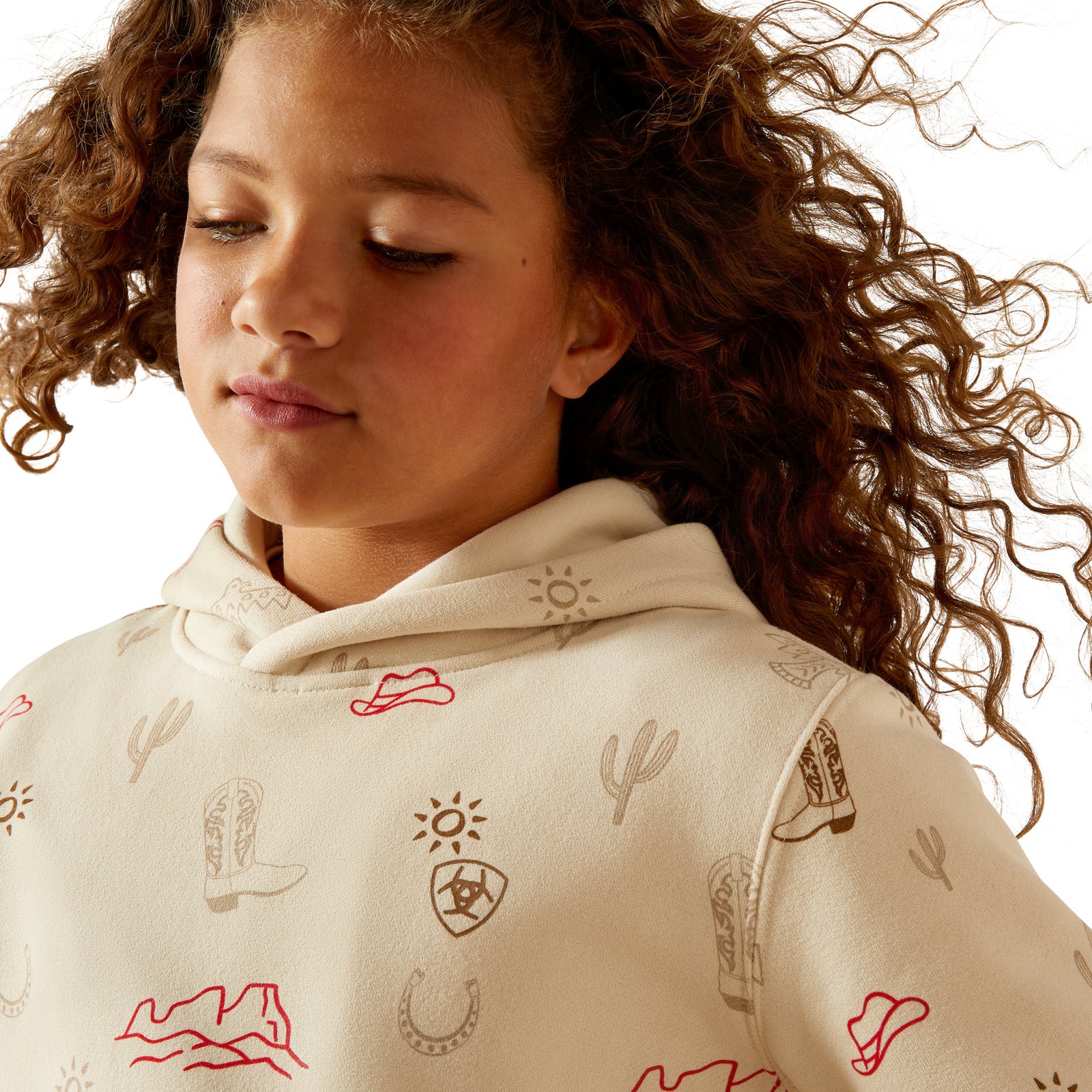 Child wearing a beige hoodie with red and black patterns on a neutral background