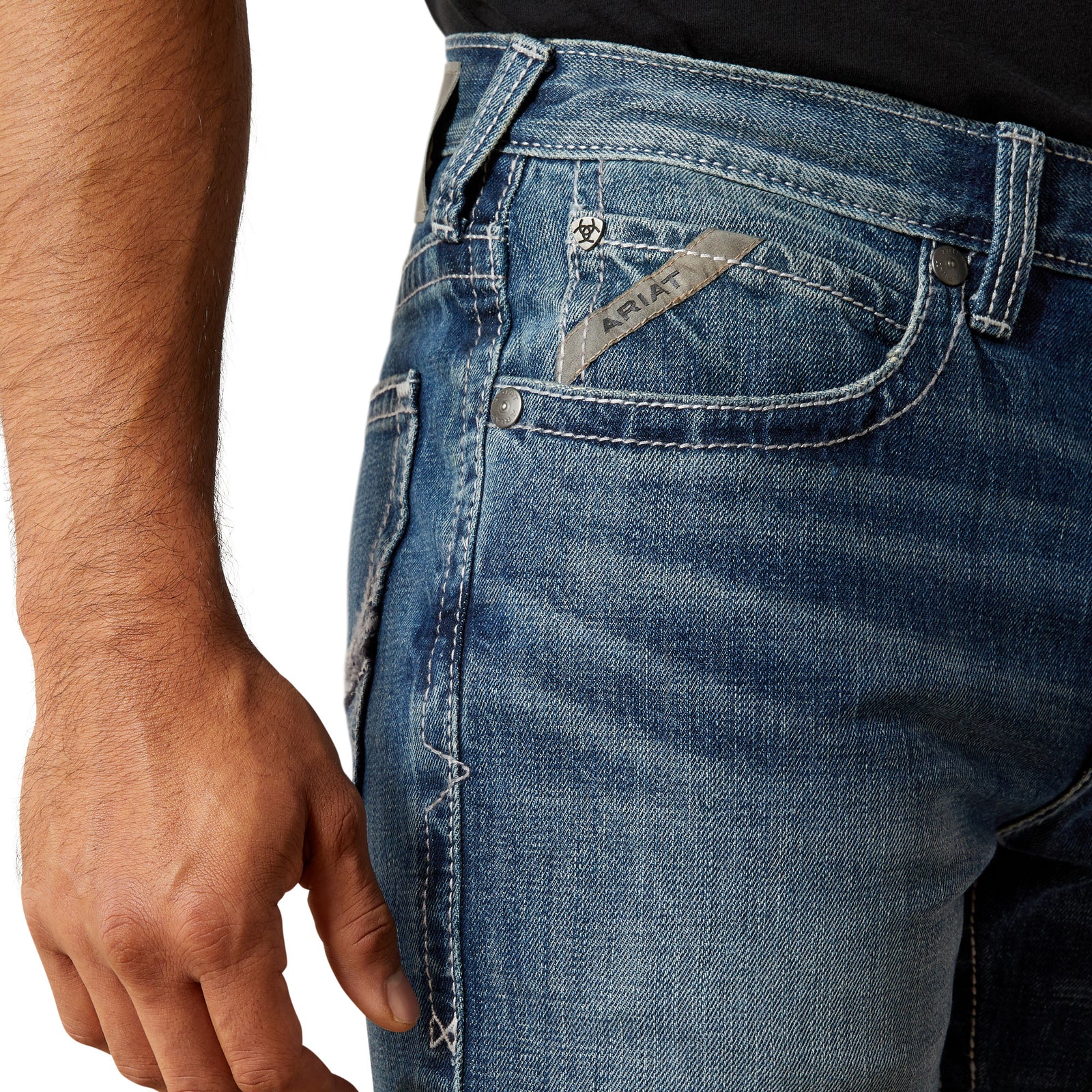 Ariat Men's M4 August Relaxed Straight Leg Jean. Close-up of blue jeans with a brand logo on a white background