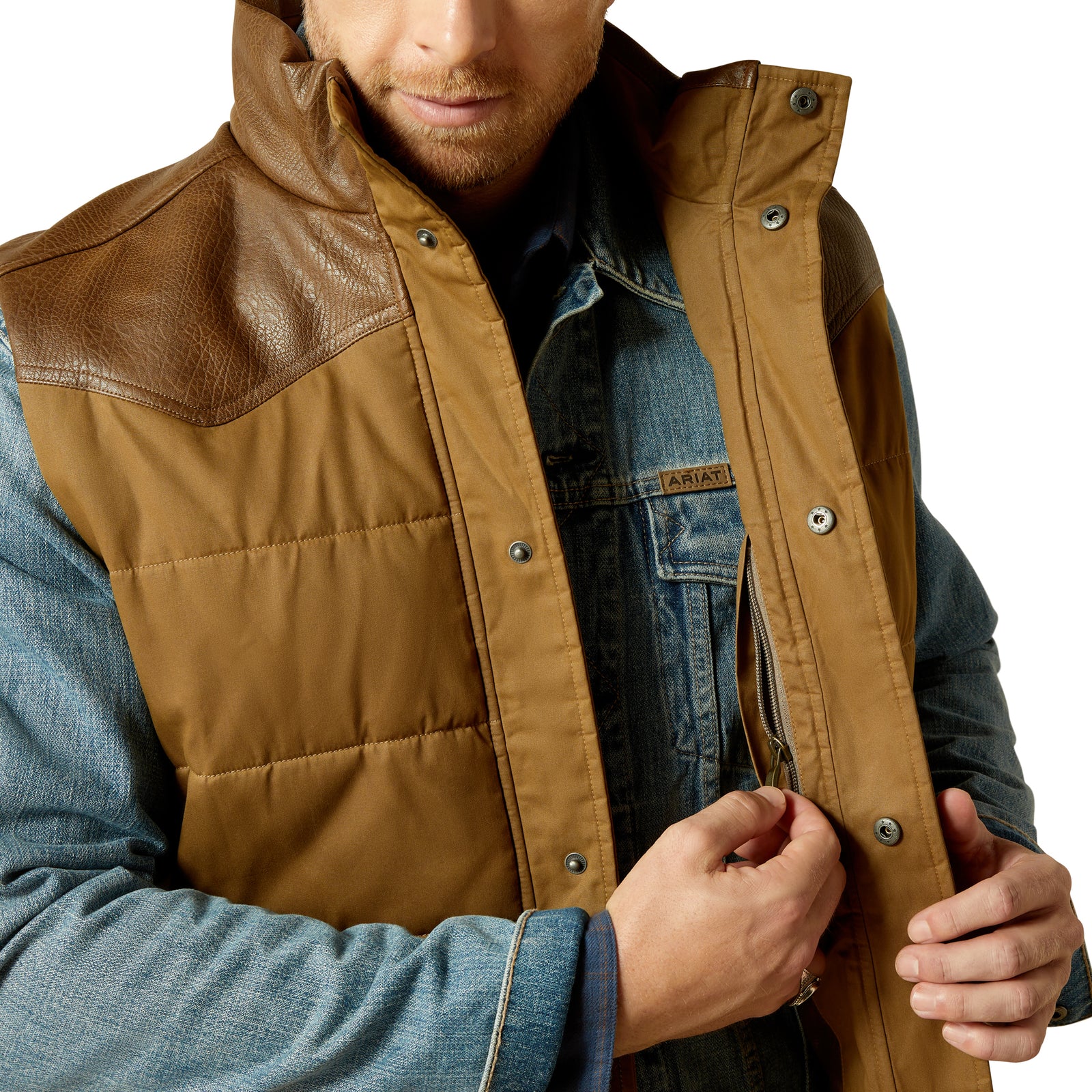 Man wearing a brown quilted vest over a denim jacket on a white background