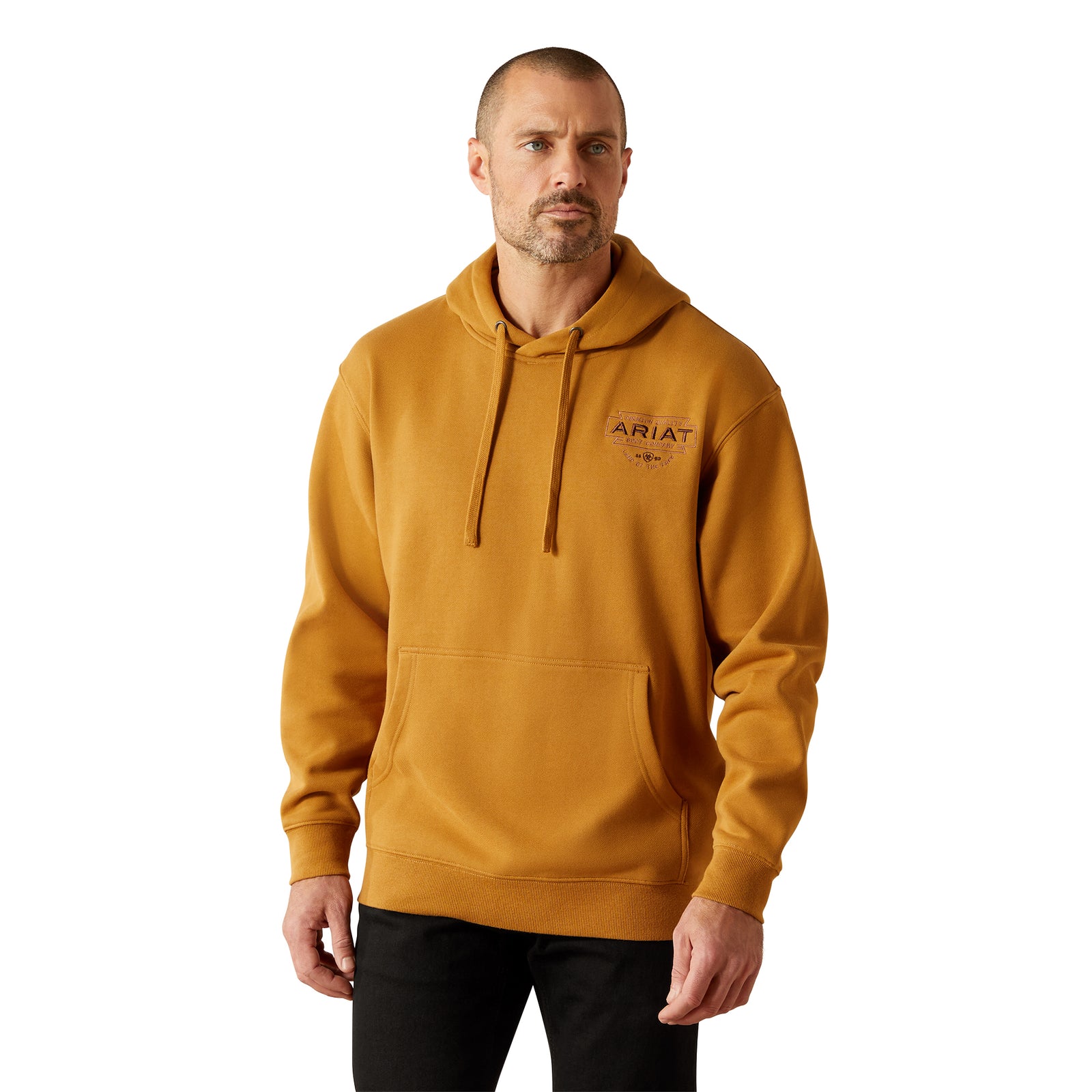 Man wearing a mustard yellow hoodie with 'Ariat' logo on a white background