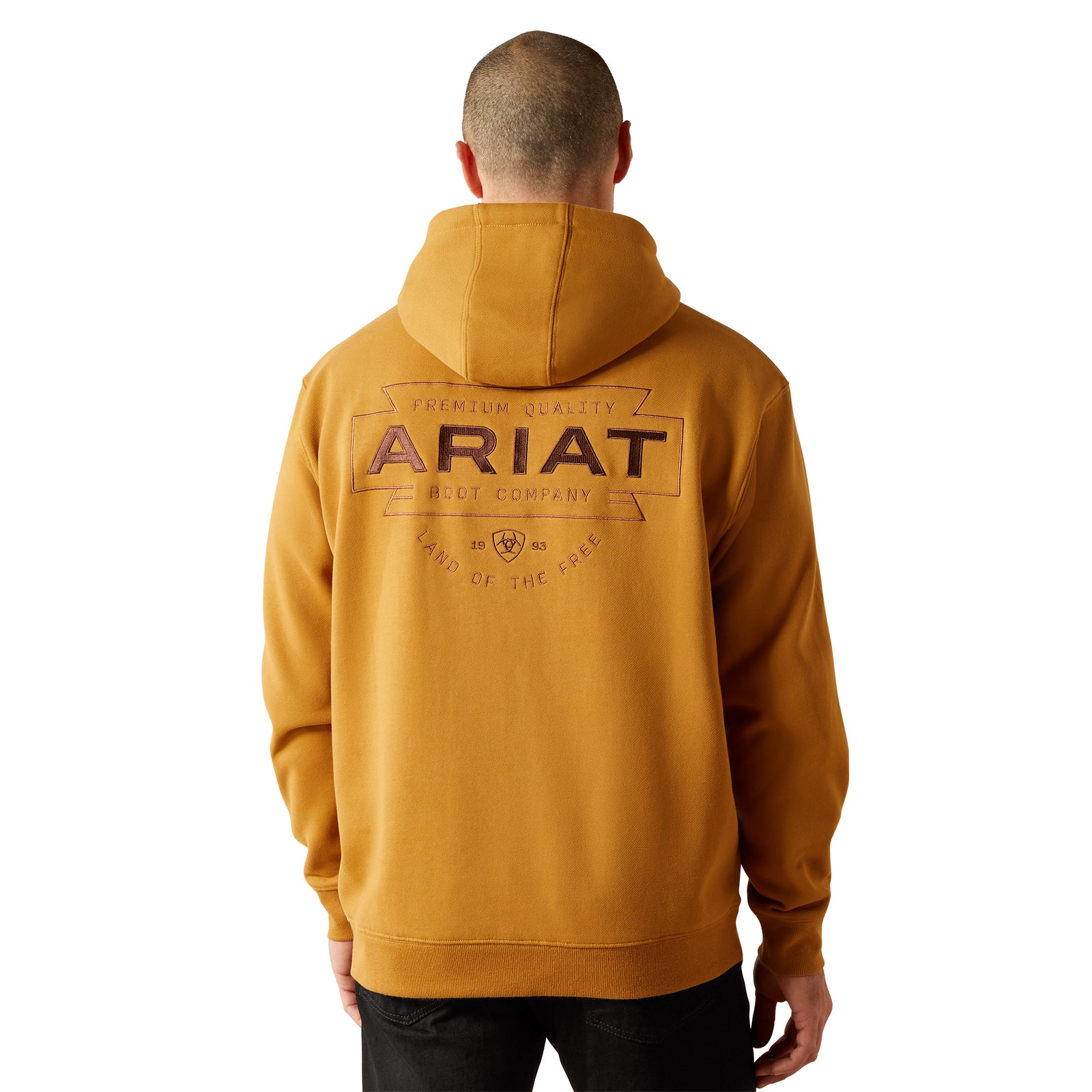 Person wearing a mustard yellow hoodie with 'Ariat' branding on the back, standing against a white background.